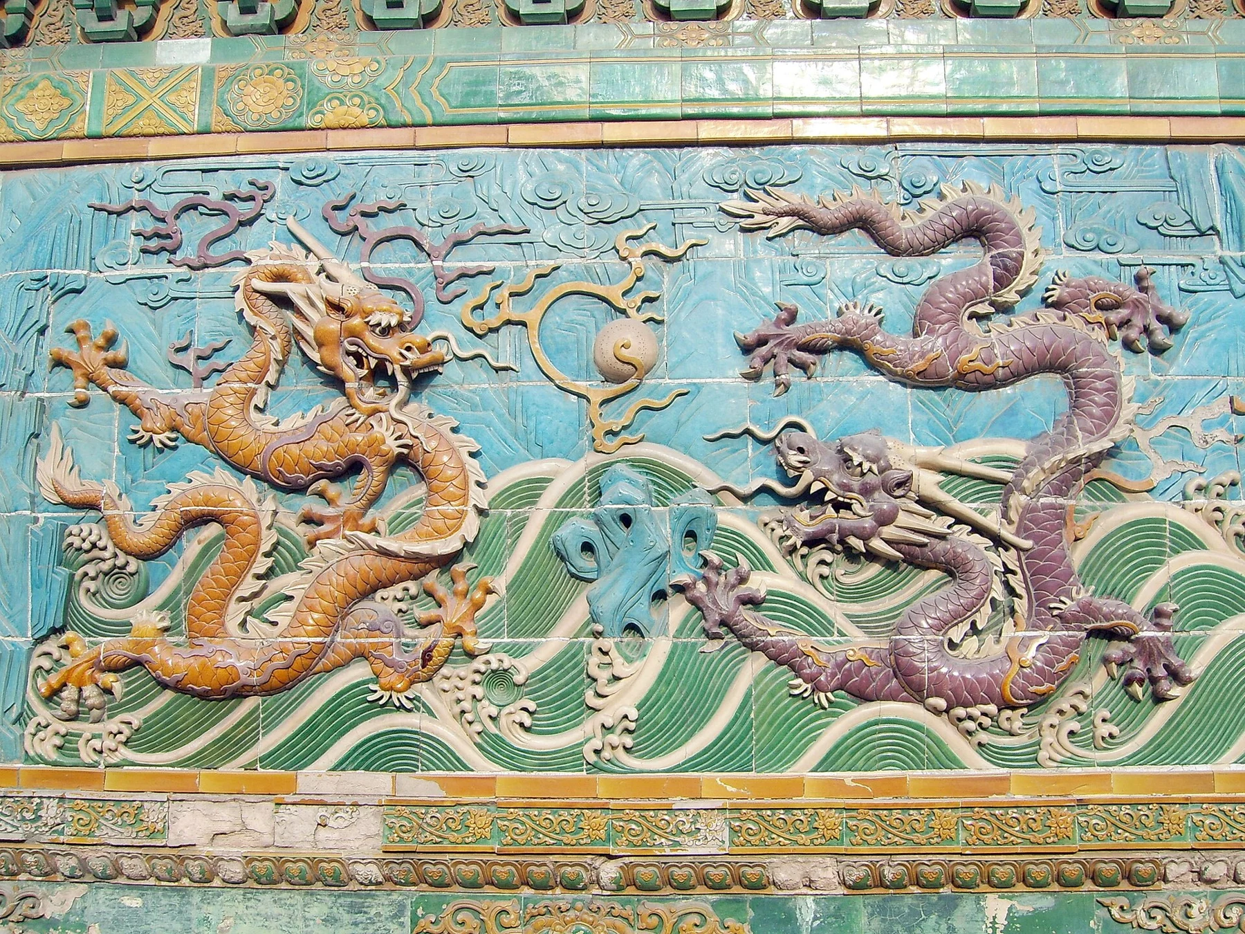 Two coloured dragon reliefs and patterned waves on Beihai’s Nine-Dragon Wall.
