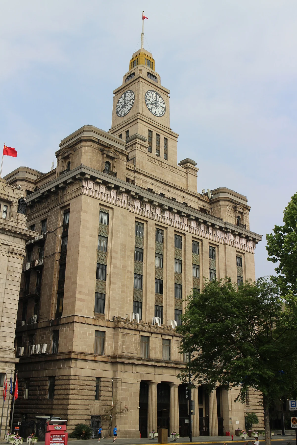 The tall clock tower and long stone facade viewed at an angle from the street.