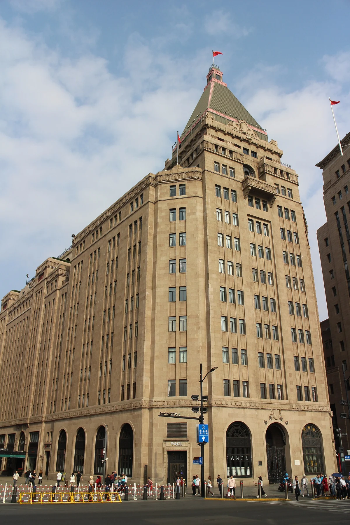 A tall stone hotel corner topped by a pointed green roof above a busy street.