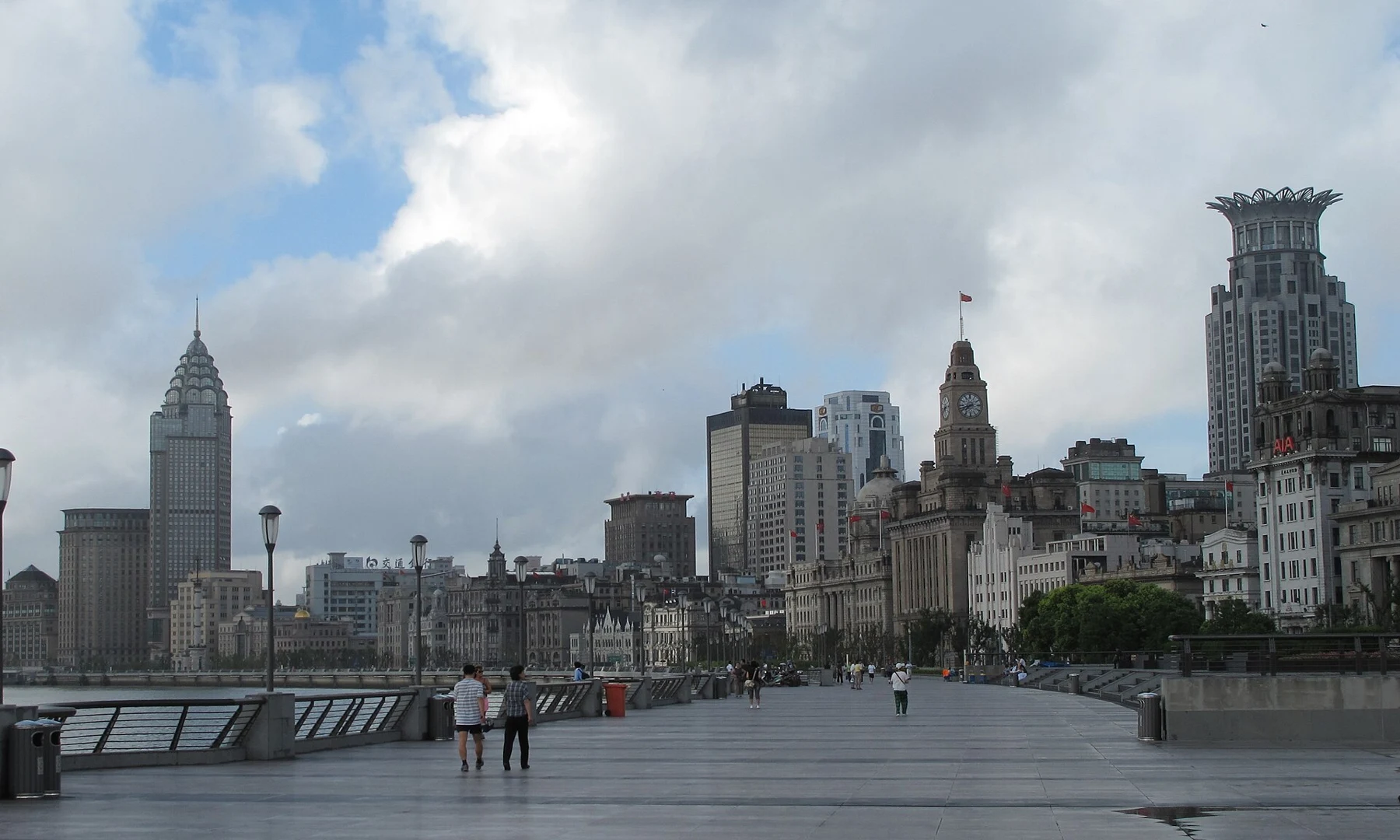 An open riverfront promenade with railings and the historic buildings beyond.