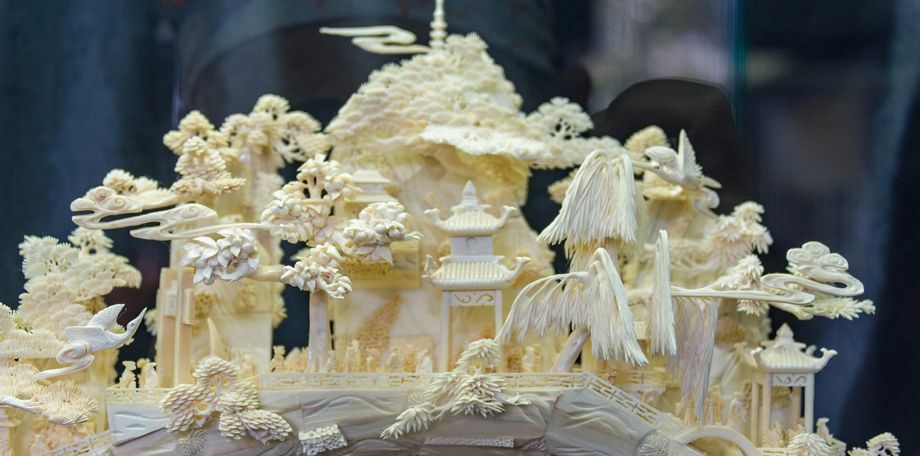 Pale carved miniature with buildings, figures and trees.