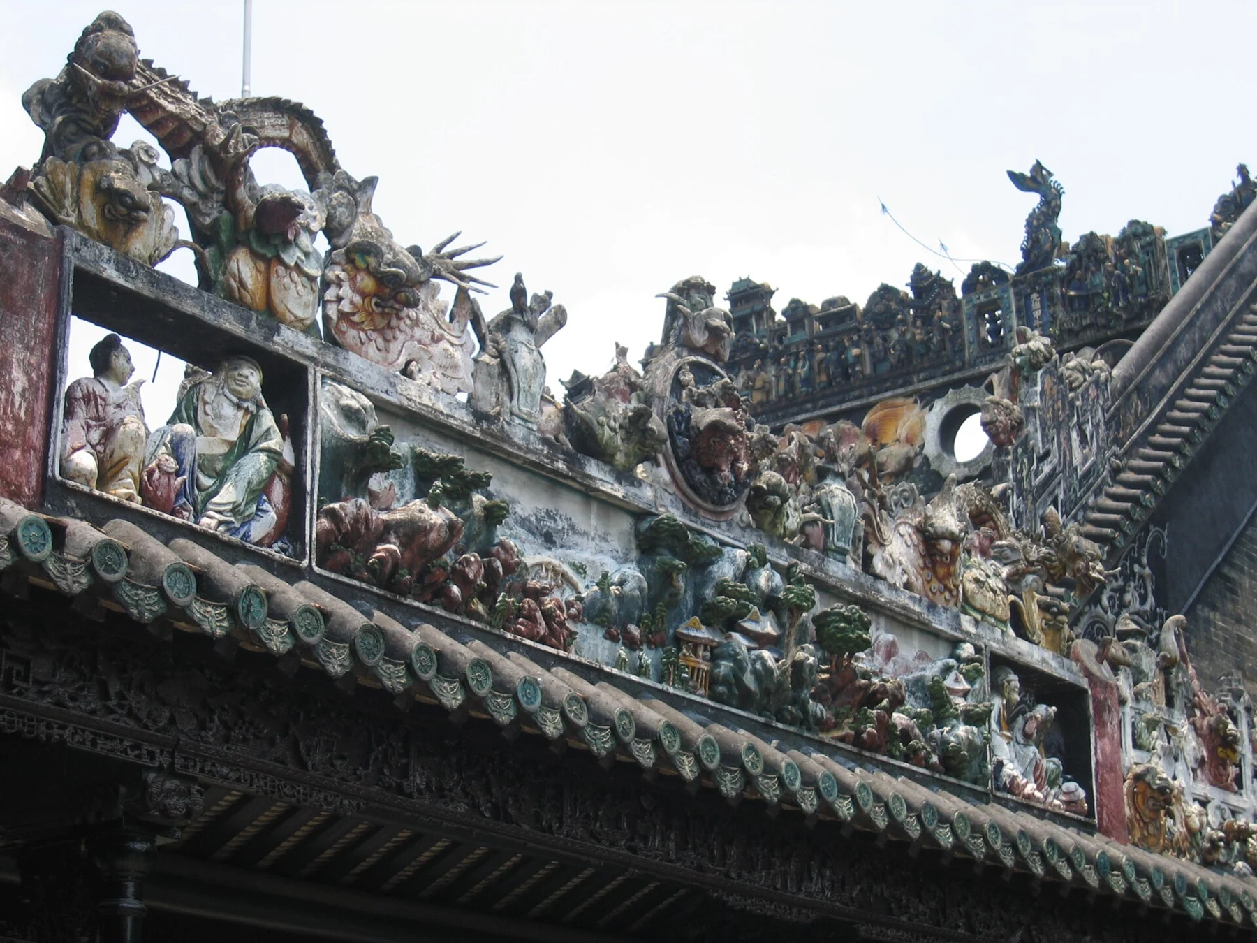 Close view of figures and small architectural forms along a decorated roof ridge.