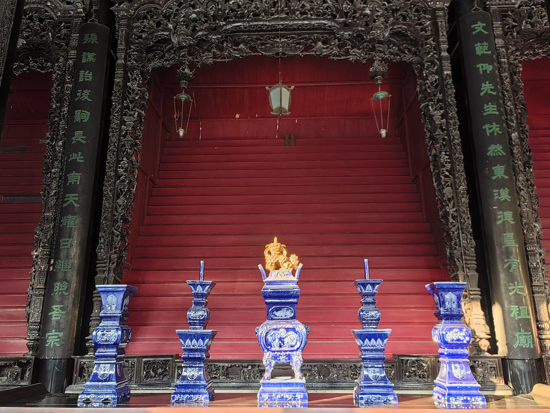 Decorative vessels, a red backdrop and an elaborate carved surround.