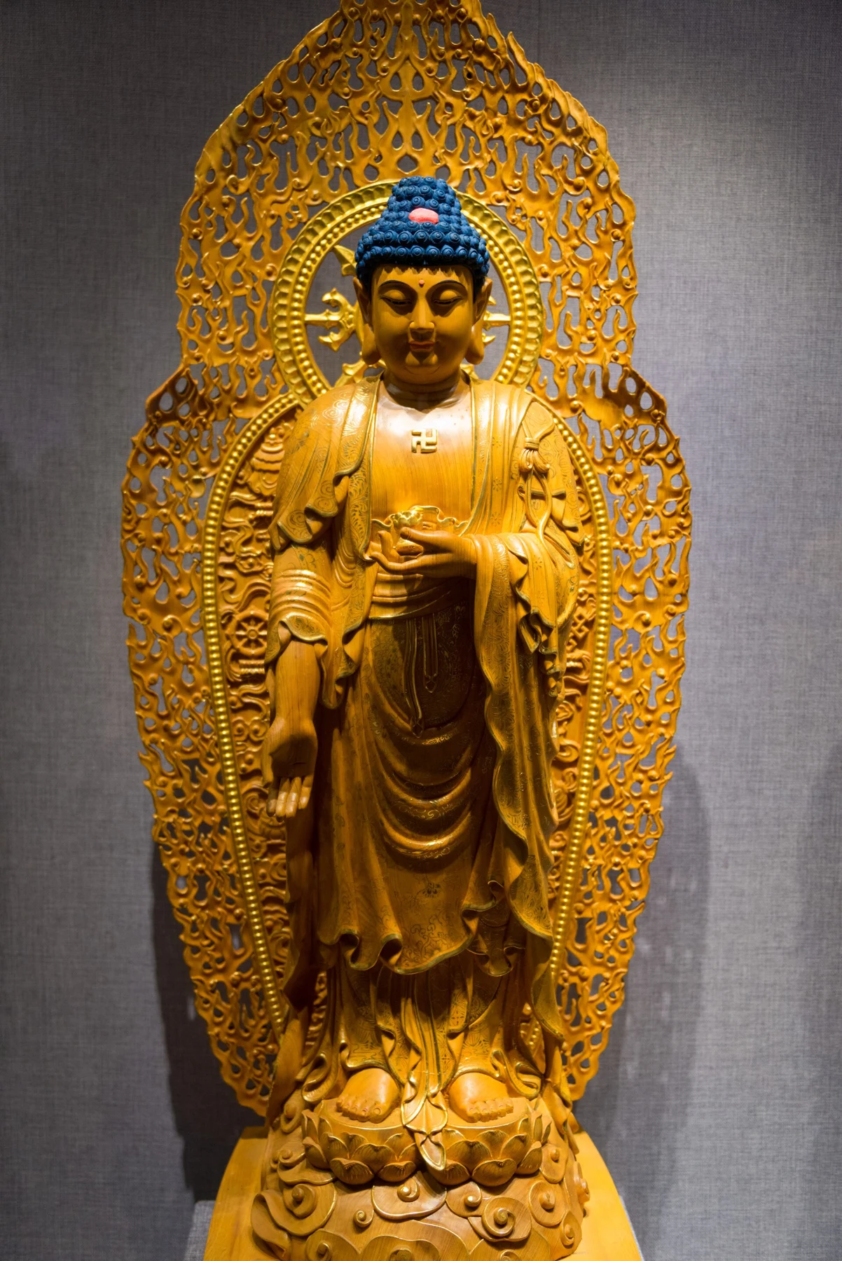 Standing gold-coloured figure within an elaborate decorative surround.