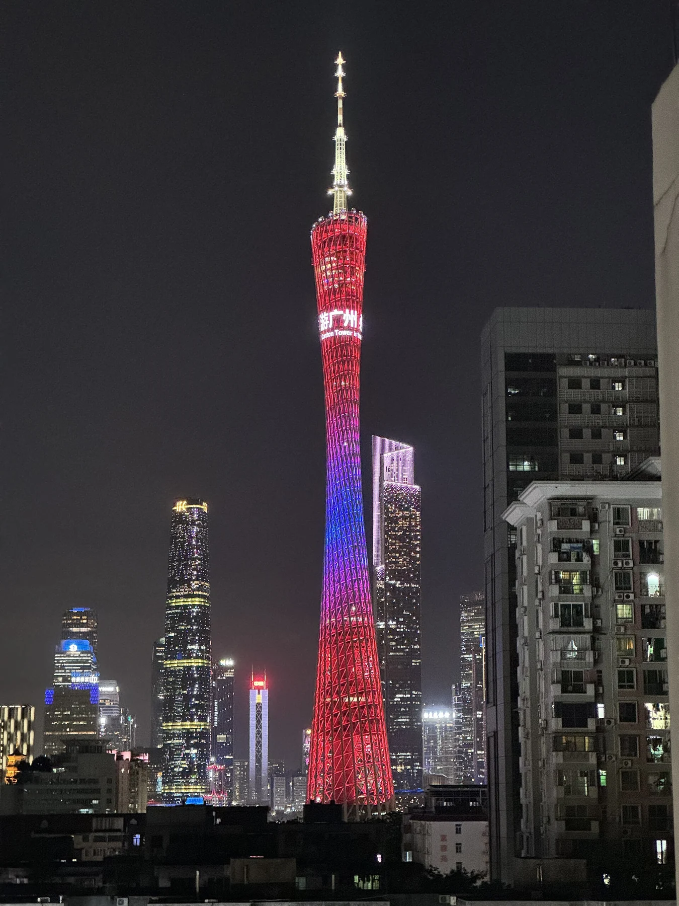 Canton Tower lit red and purple above surrounding buildings.