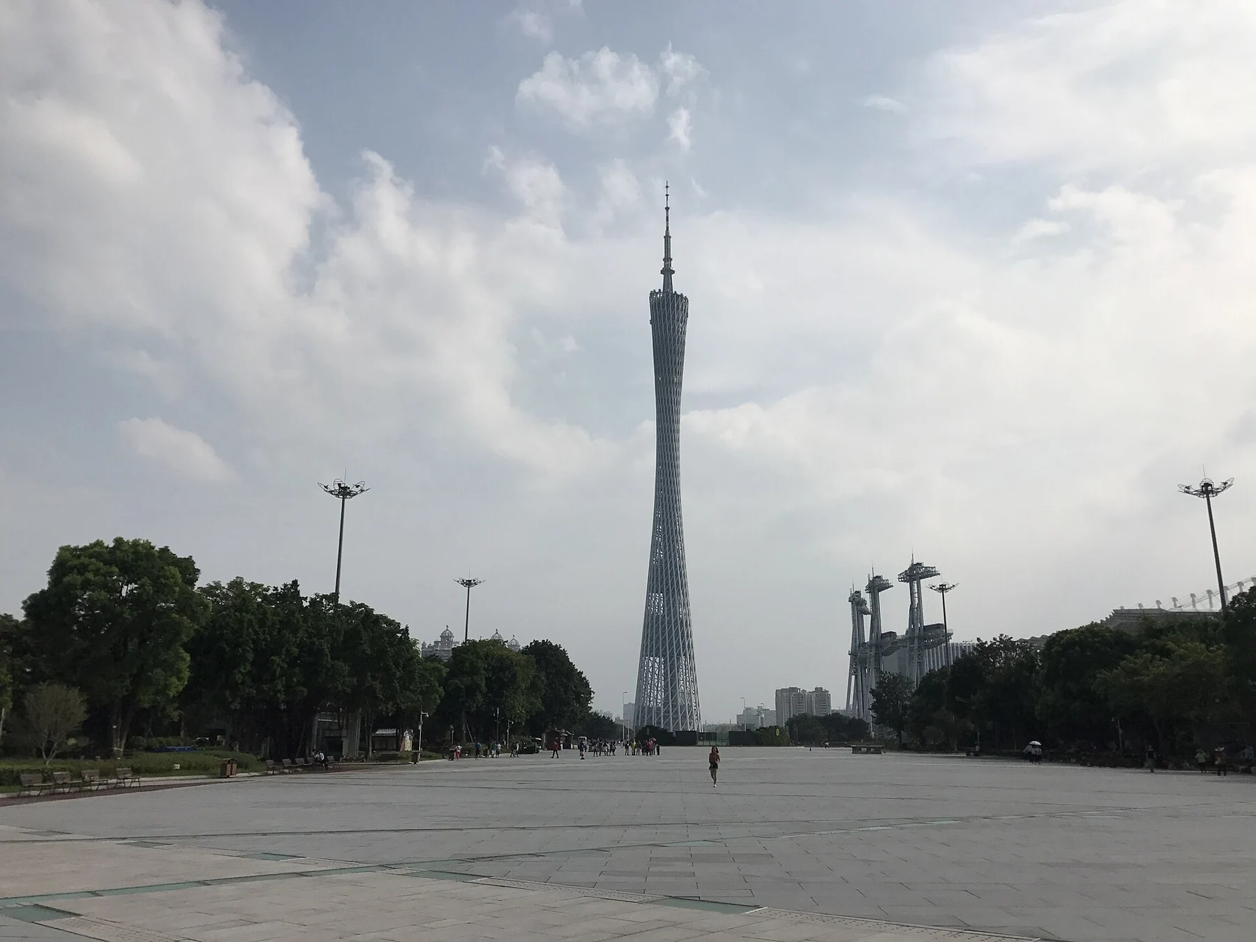 Tower seen beyond the open paved space near Guangzhou Library under a cloudy sky.