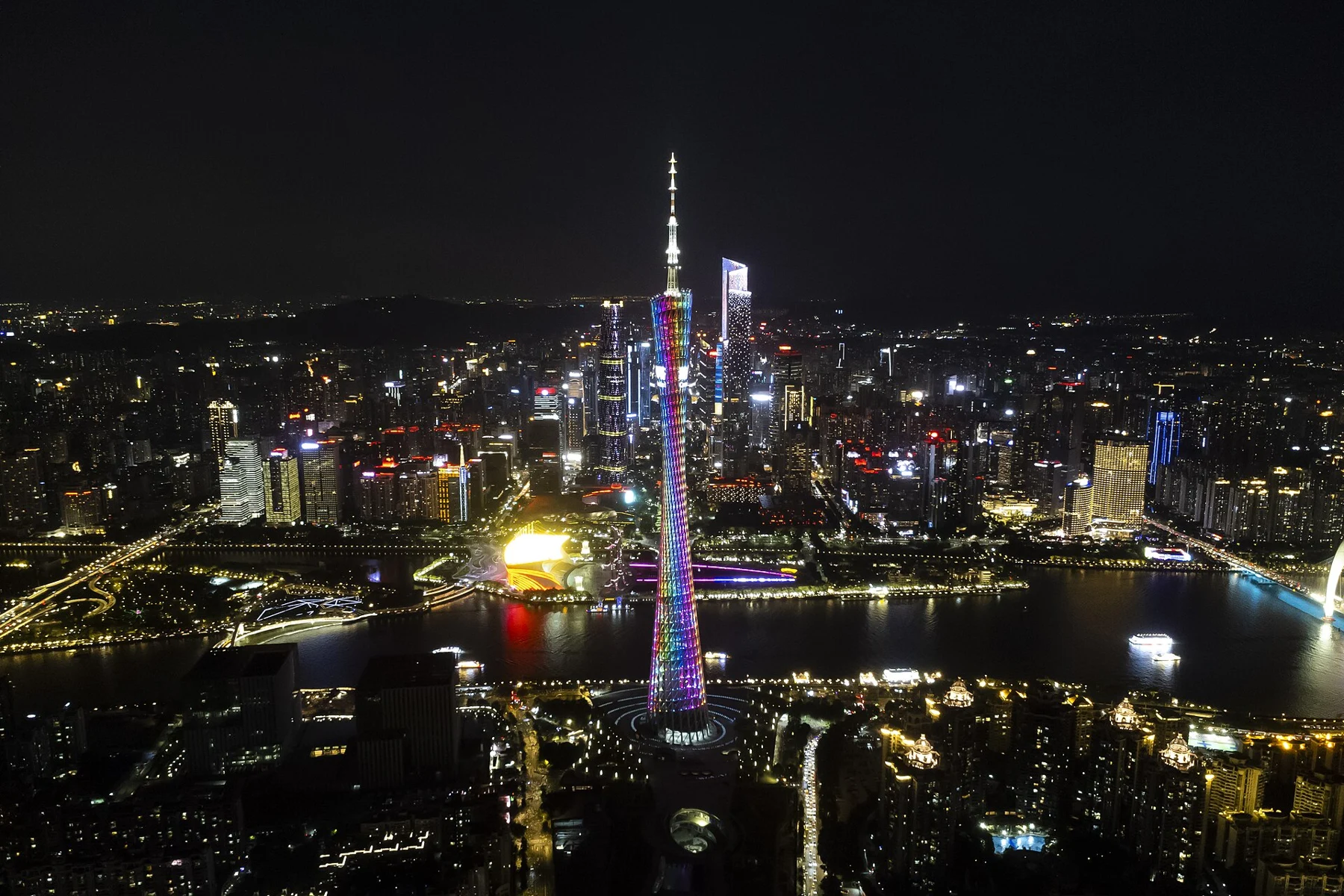 Canton Tower illuminated within a broad night-time city and river panorama.