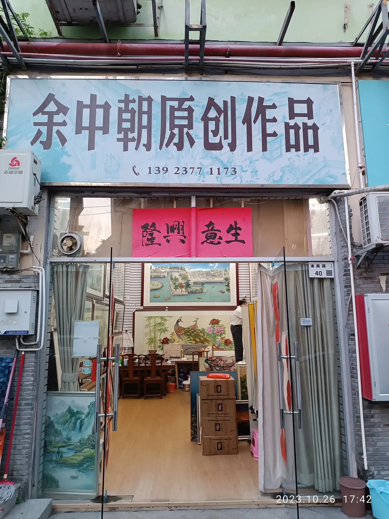 Chinese sign advertising original works above an open picture shop with frames, paintings and boxes