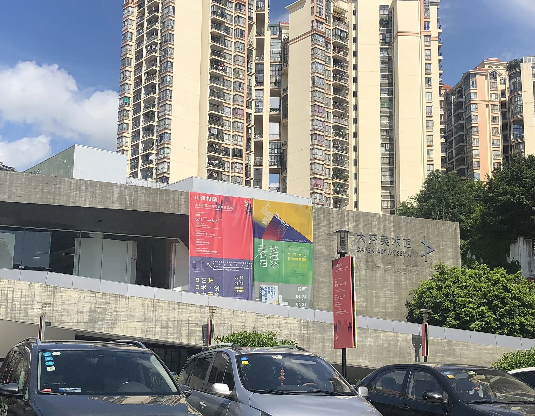Concrete museum facade bearing its Chinese and English name, past exhibition banners and neighbouring apartment towers