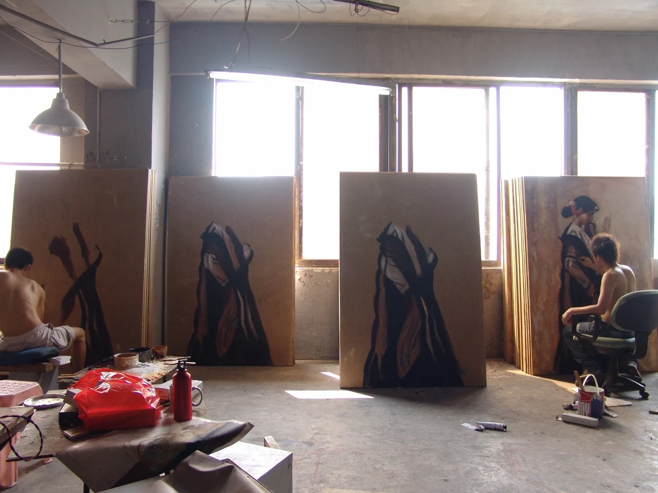 Painters at work among several canvases showing similar compositions at different stages