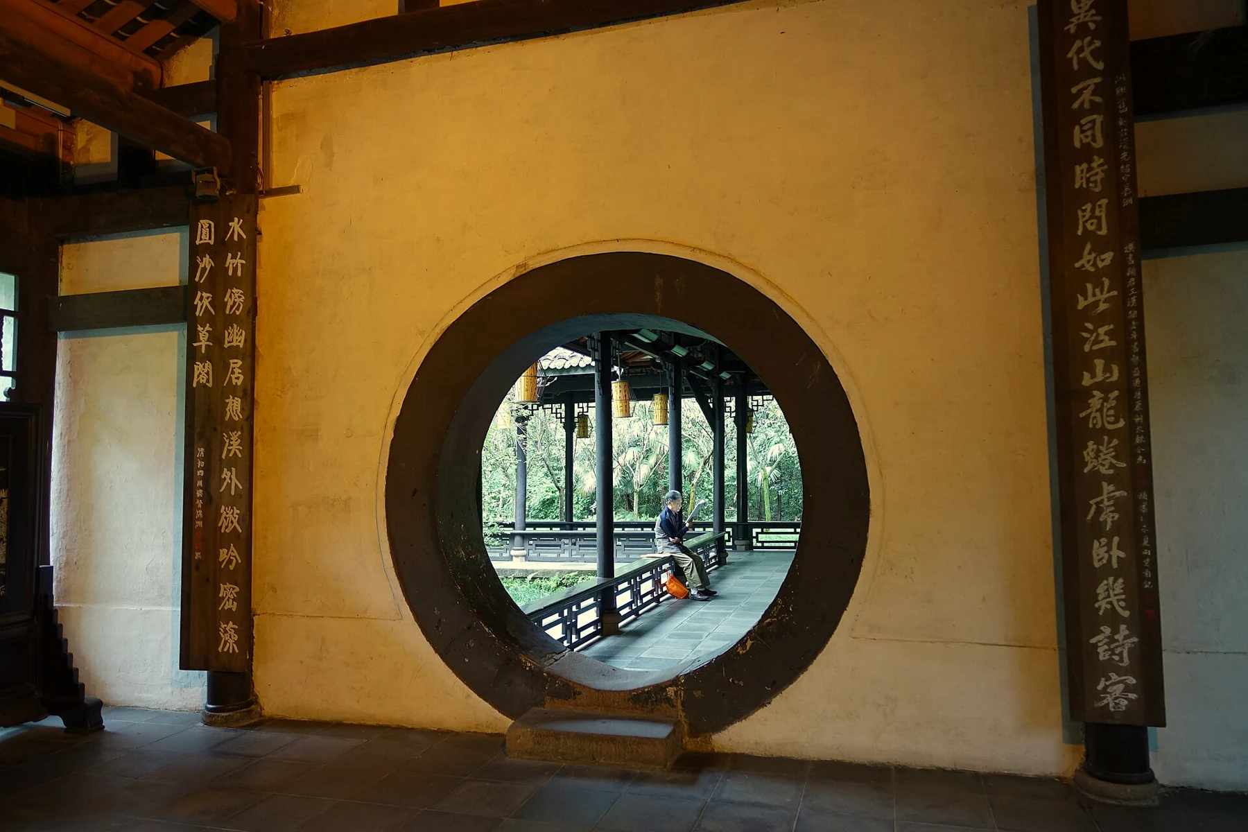 A circular doorway frames a covered corridor and a reader, photographed in 2015.
