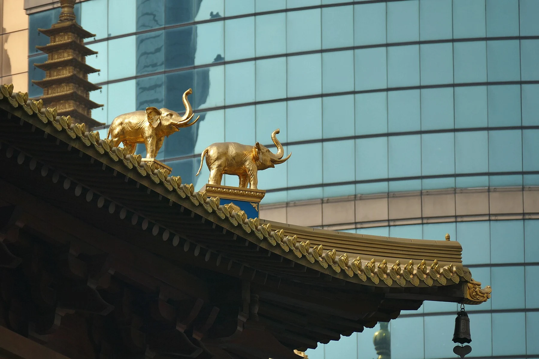 Two gilded elephant forms silhouetted above a temple roof.