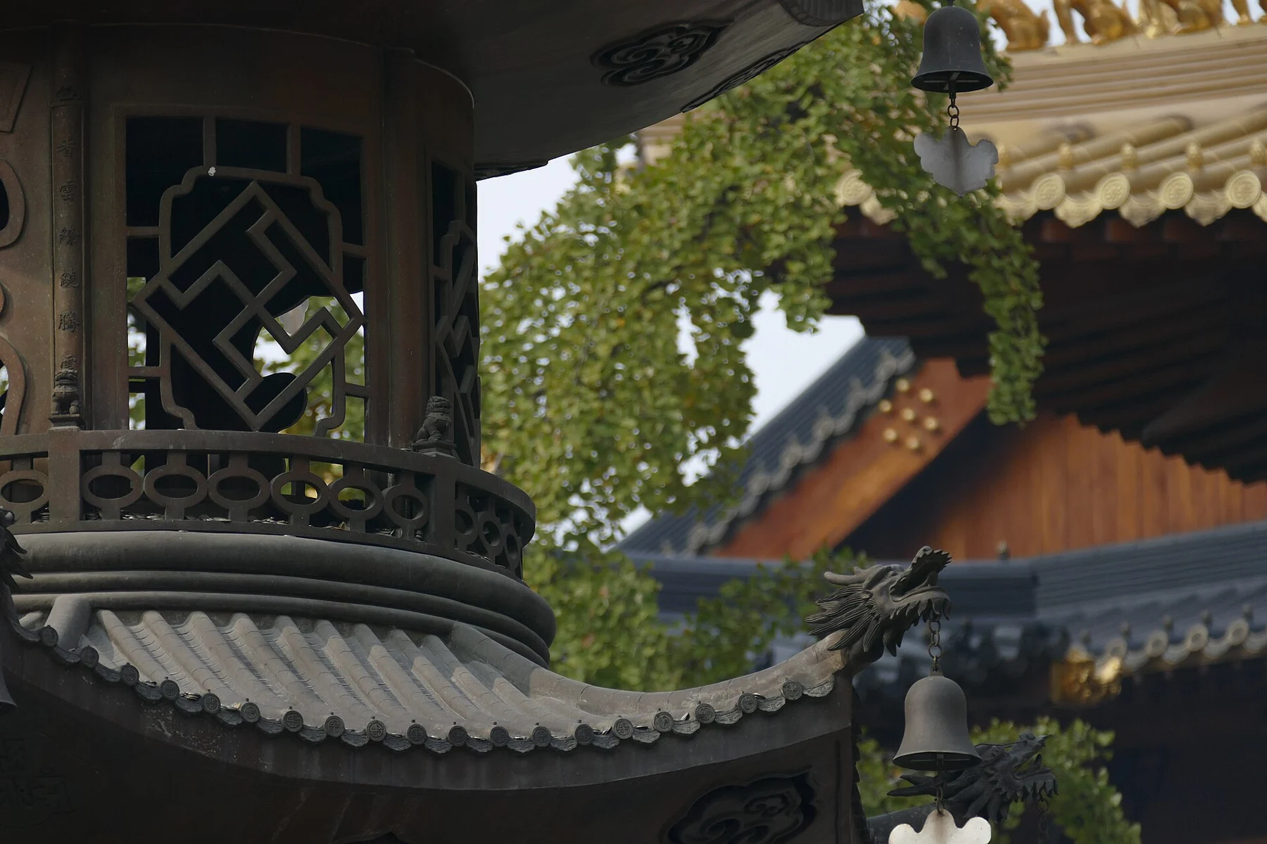 A perforated metal structure at left frames the layered temple roof behind it.