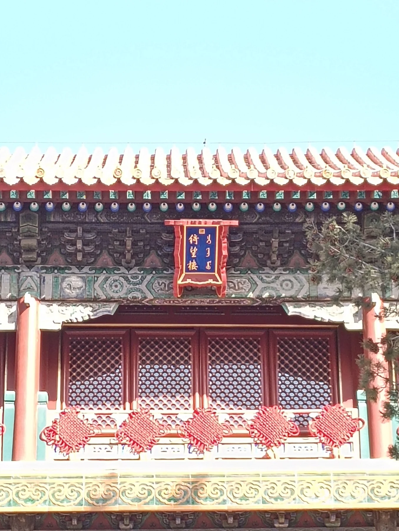 Manchu and Chinese characters on the Qiwang Lou plaque beneath painted eaves.
