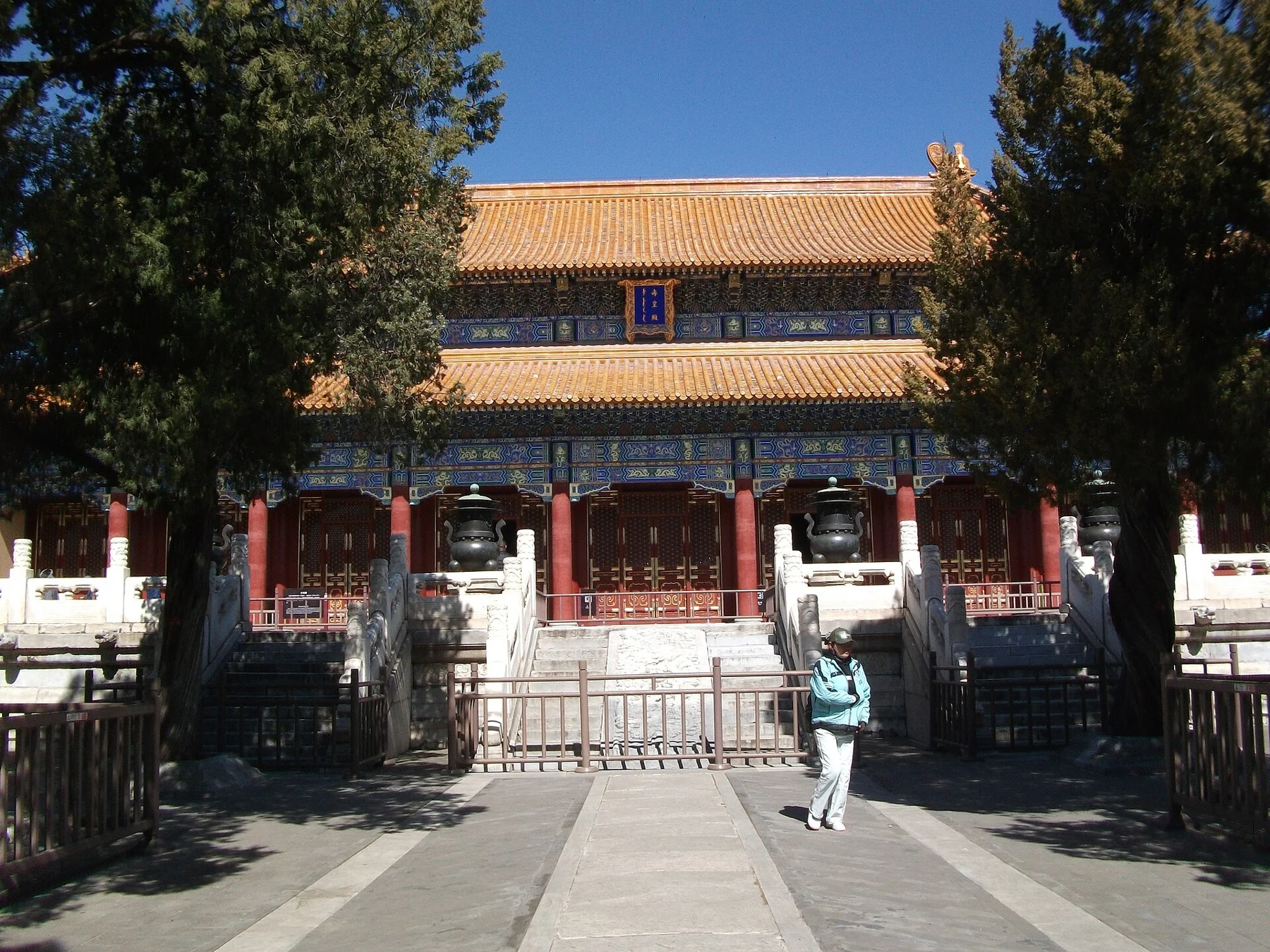 The yellow-tiled, painted facade of Shouhuang Hall behind a stone terrace and cypress trees.