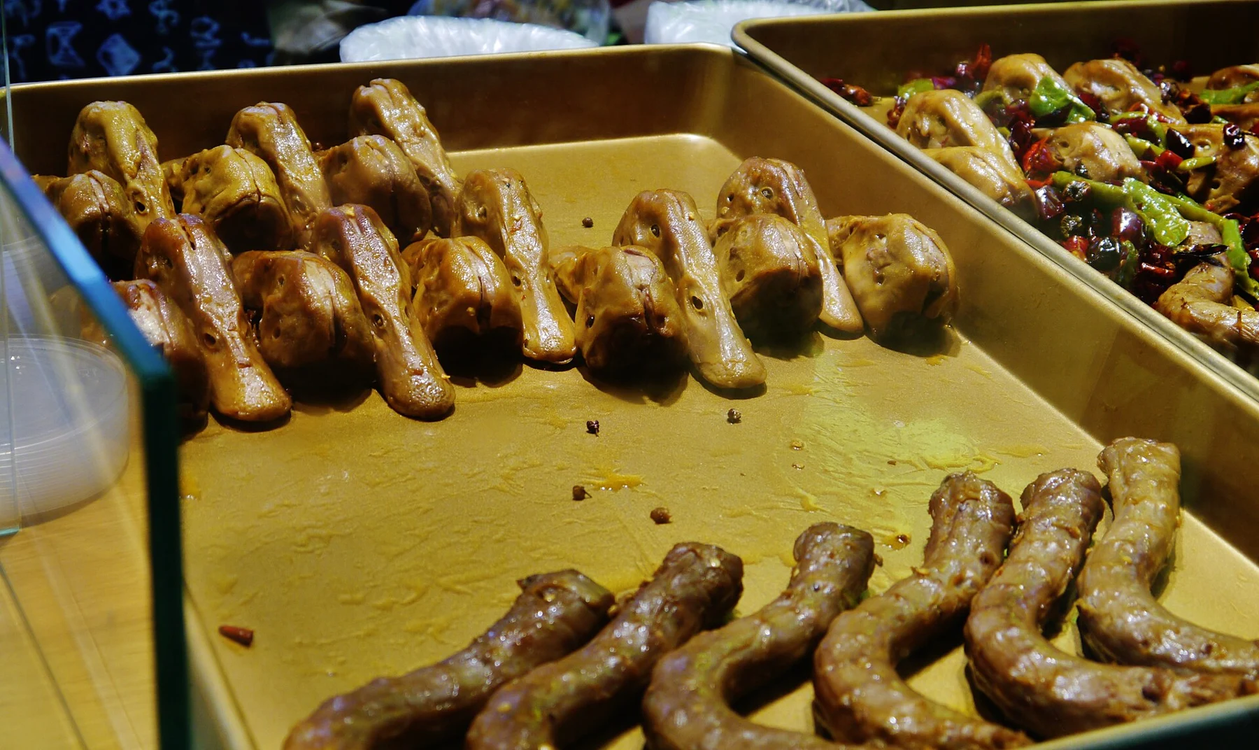 Prepared duck heads and other foods displayed in metal trays