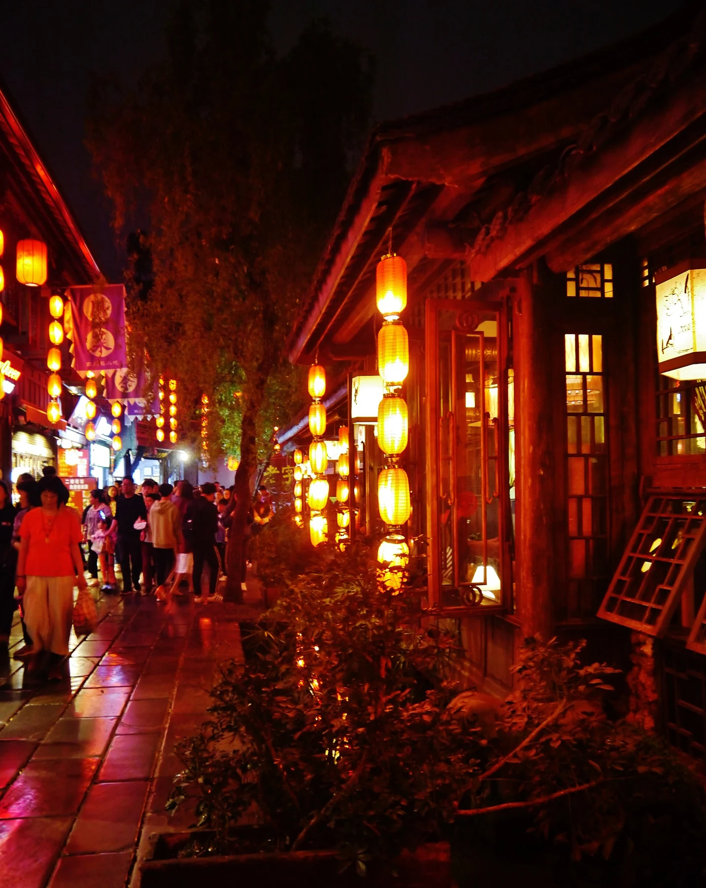 Warm lanterns and timber doors along a darker lane