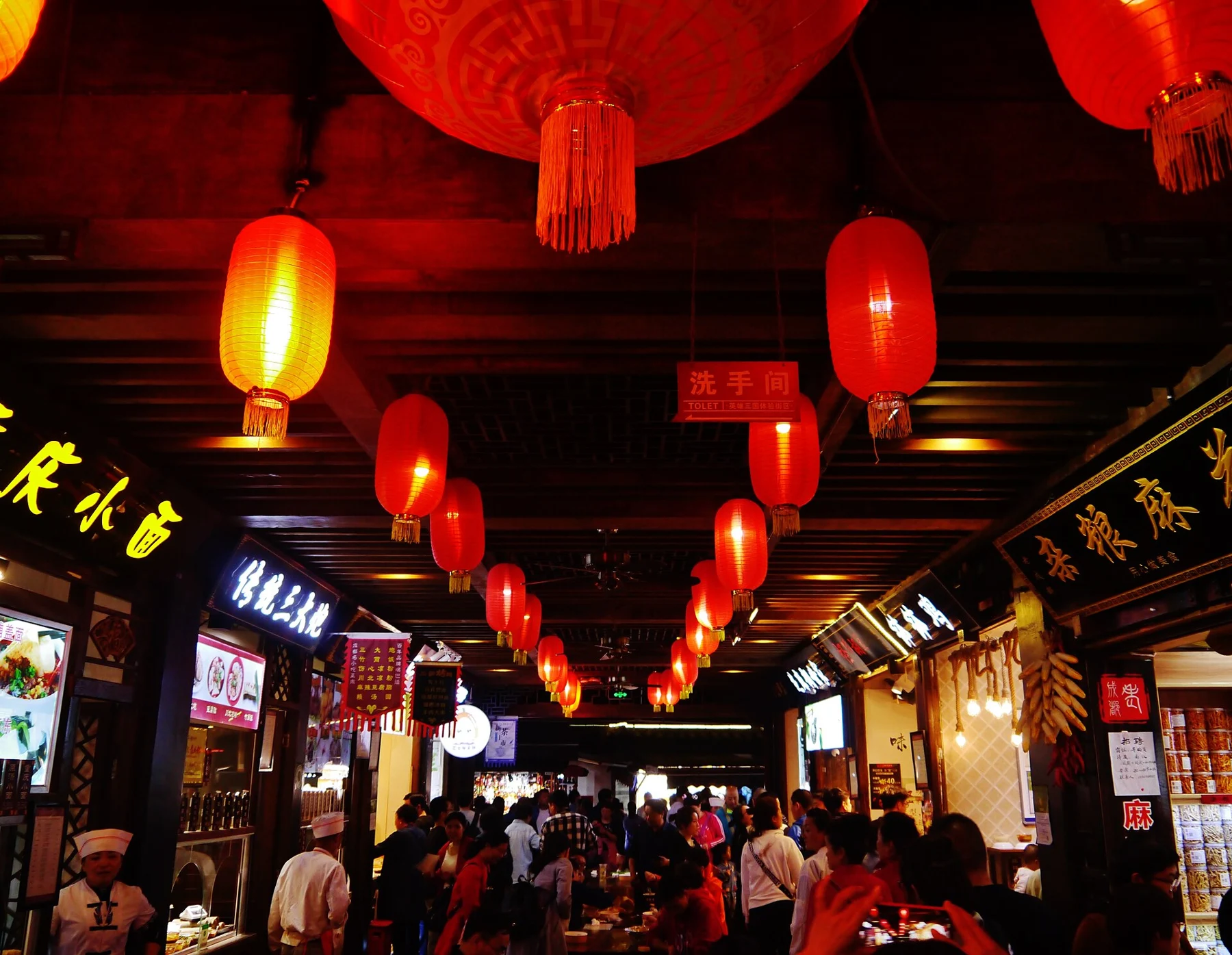 Red and yellow lanterns hanging above a covered shopping lane