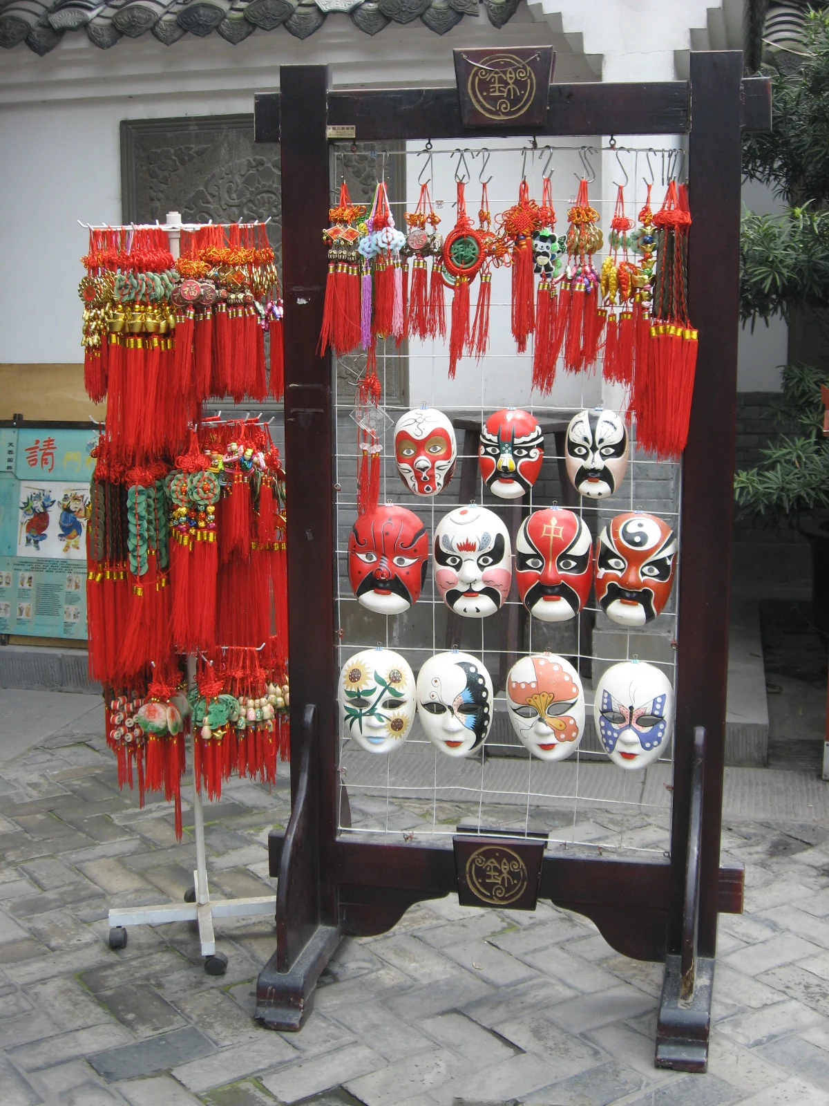 Display rack of small painted masks and hanging red decorations
