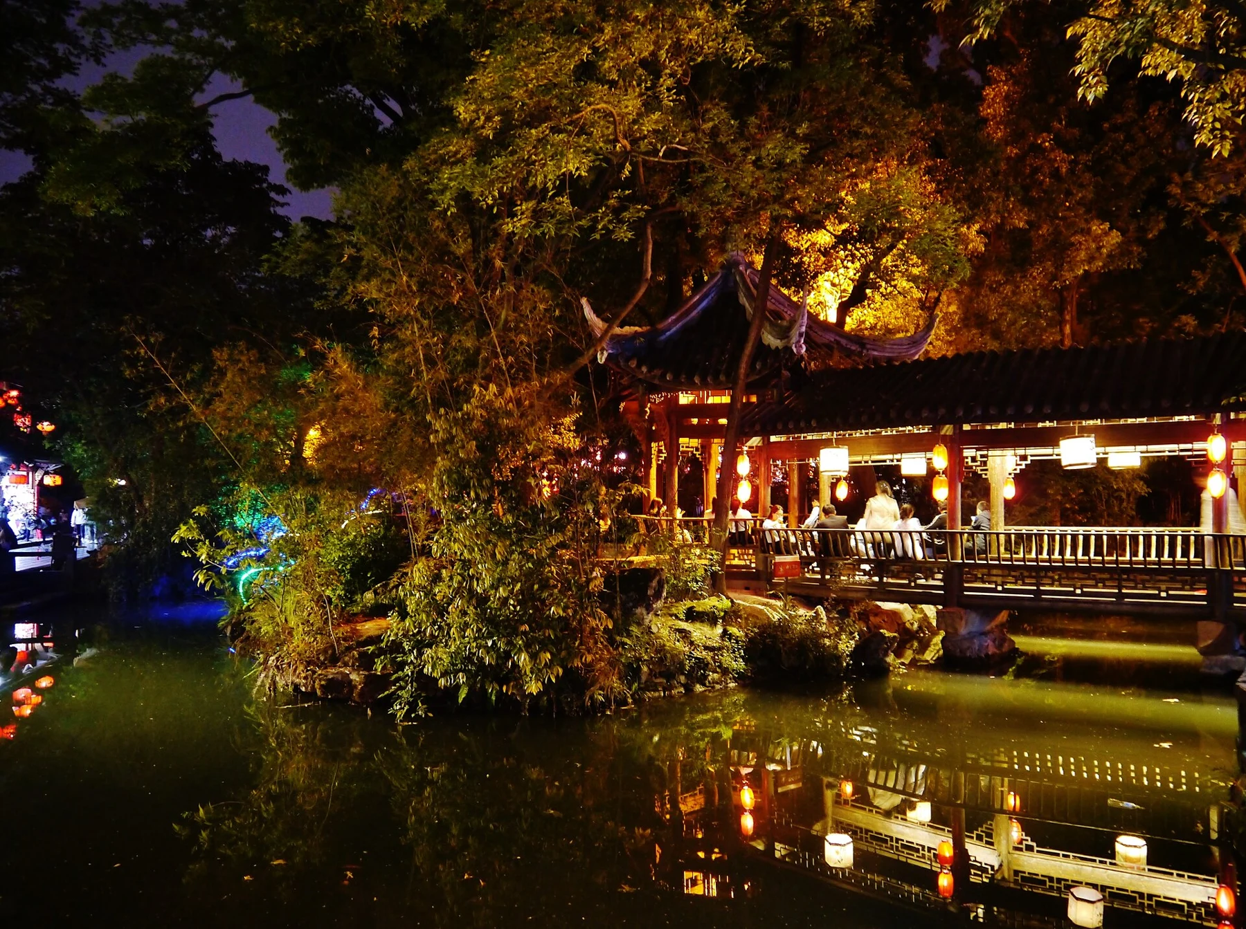 Illuminated timber frontage and trees reflected in water at night