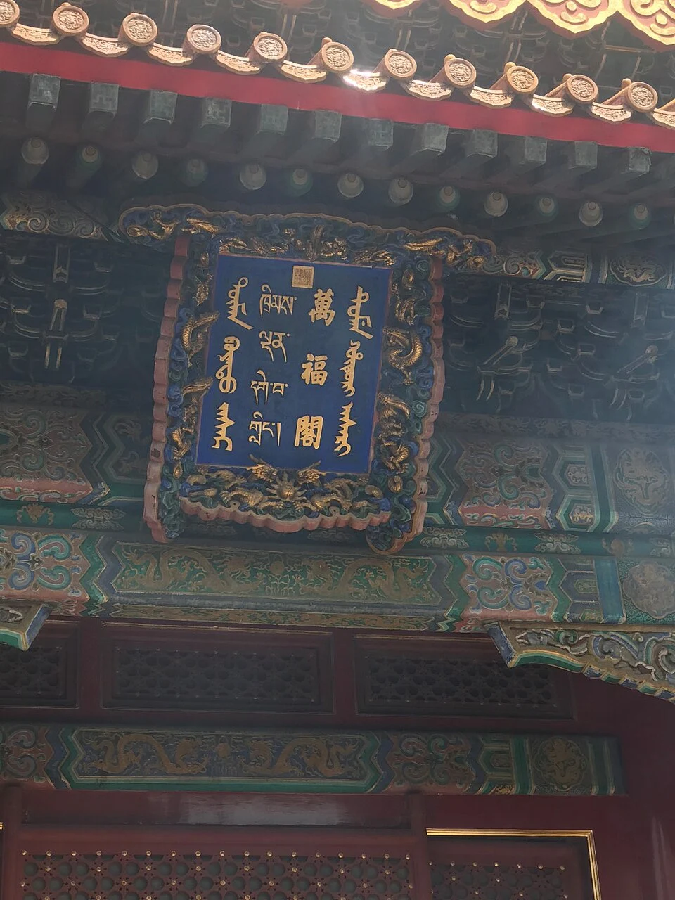 The Wanfu Pavilion name plaque below painted roof brackets.