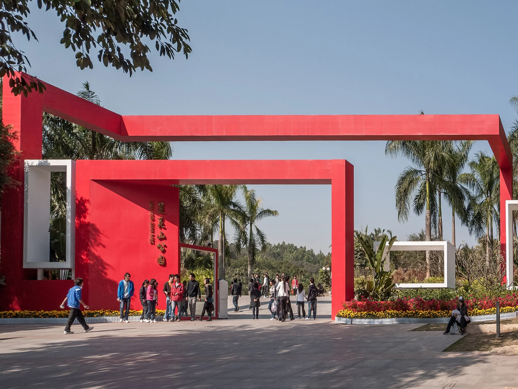 Red rectangular entrance structure, park name, palms and visitors