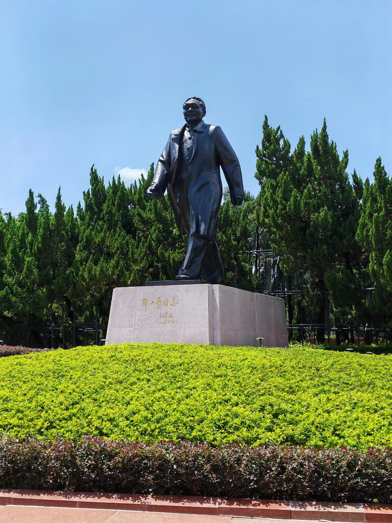 Bronze figure of Deng Xiaoping walking forward on a stone plinth