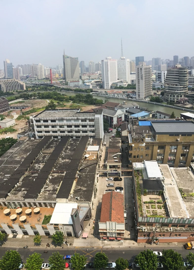 Low factory roofs and narrow internal spaces beside Suzhou Creek and taller city buildings.