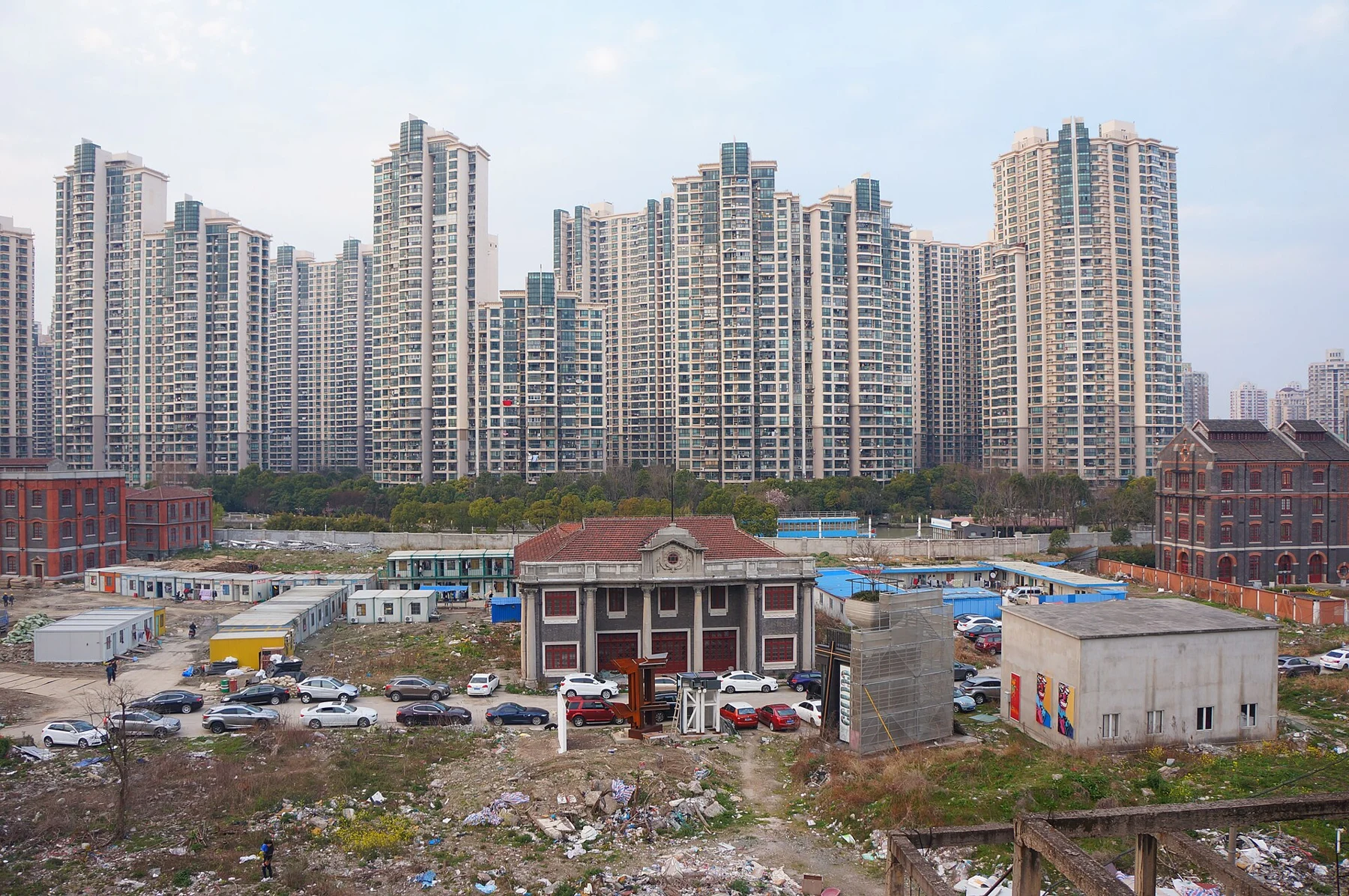Tall residential towers across a river bend with low buildings and a construction area in front.