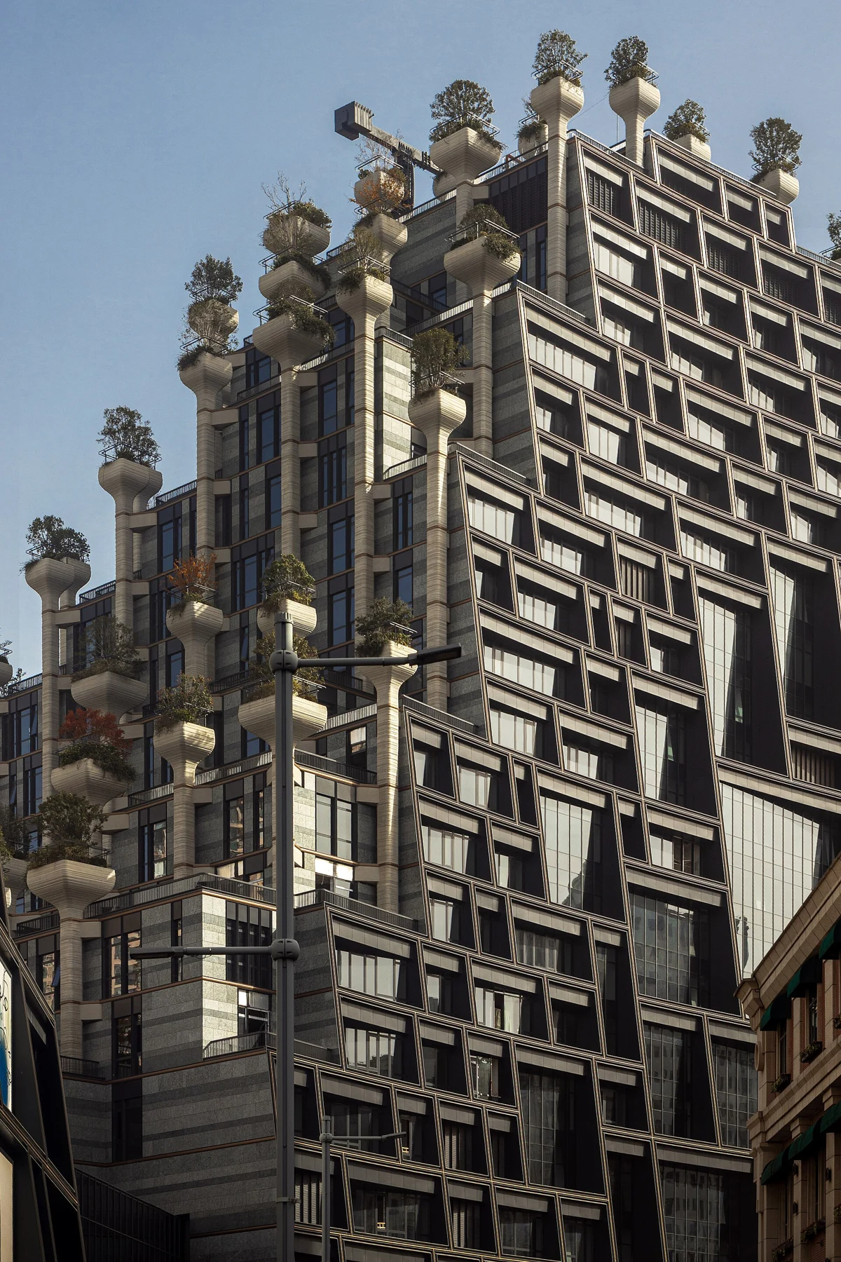 A tall stepped building with projecting planters, trees and dense terrace structures.