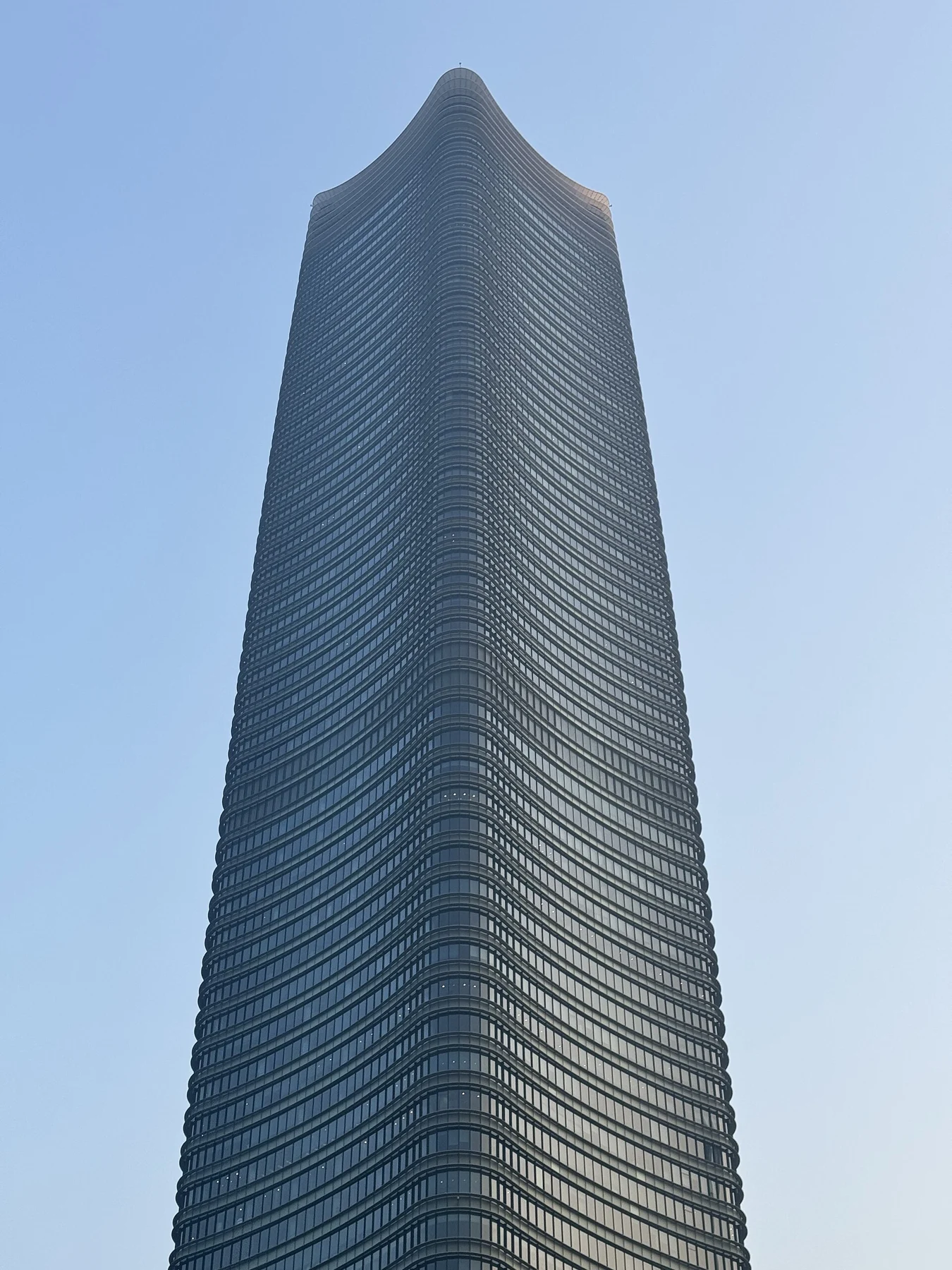 A tall dark-glazed tower with a gently shaped crown seen from below.
