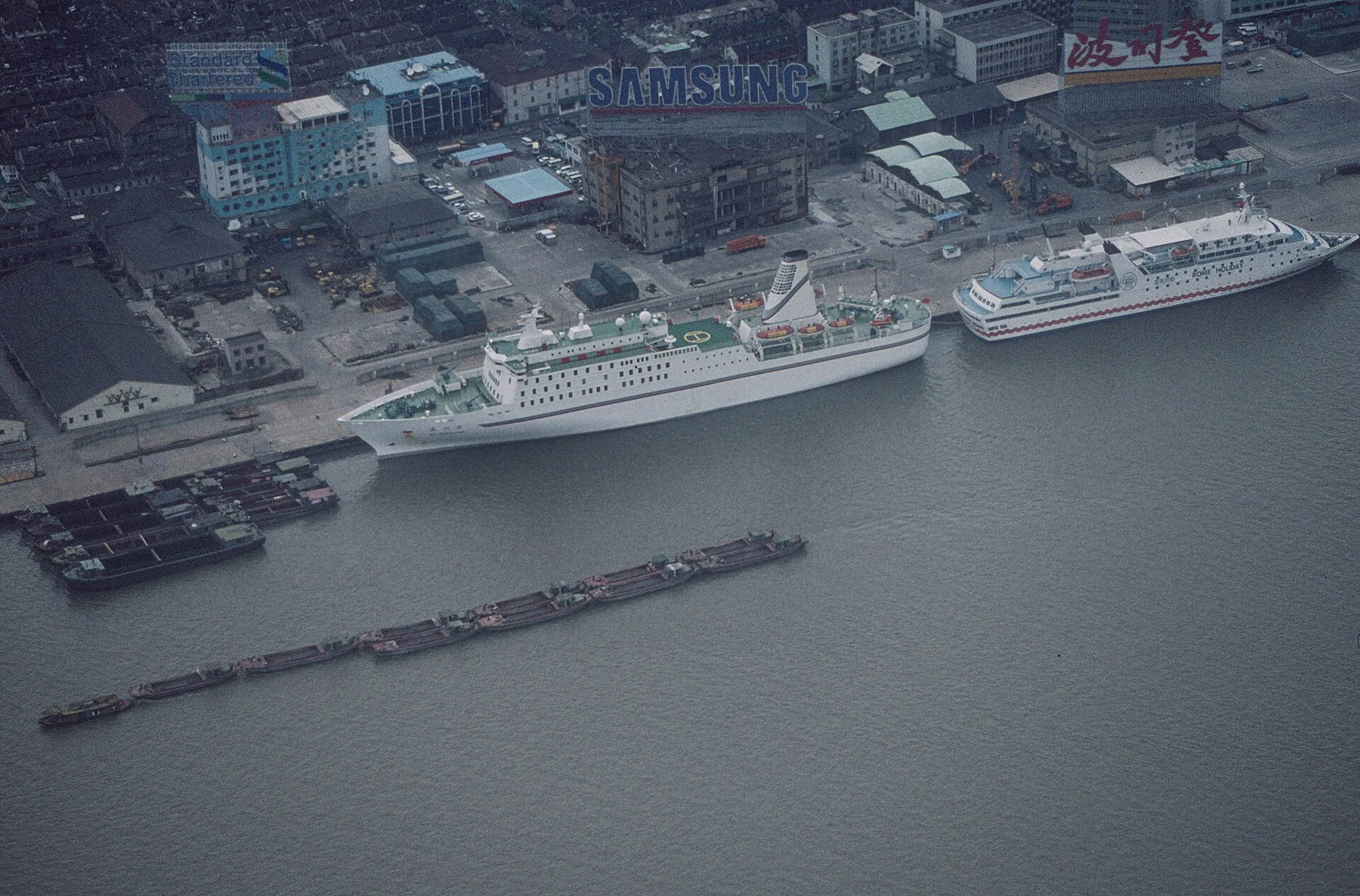 An elevated historical view of passenger ships, quays, warehouses and river traffic.