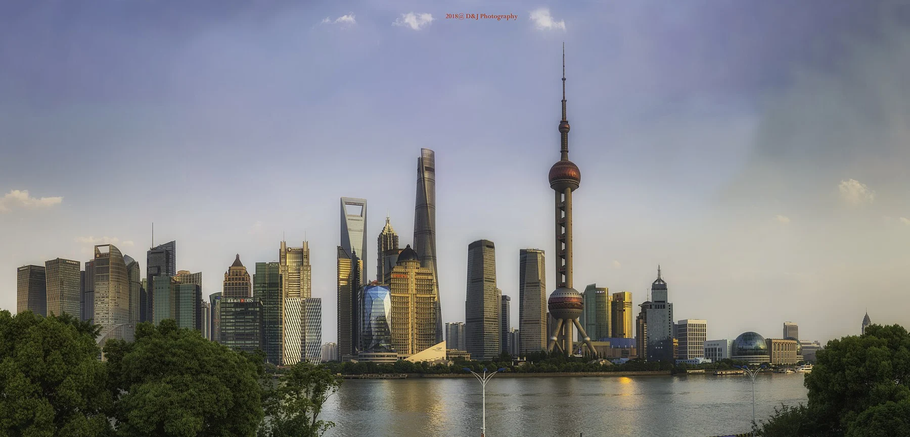 The Oriental Pearl and financial-district towers beyond the river, under an evening sky.