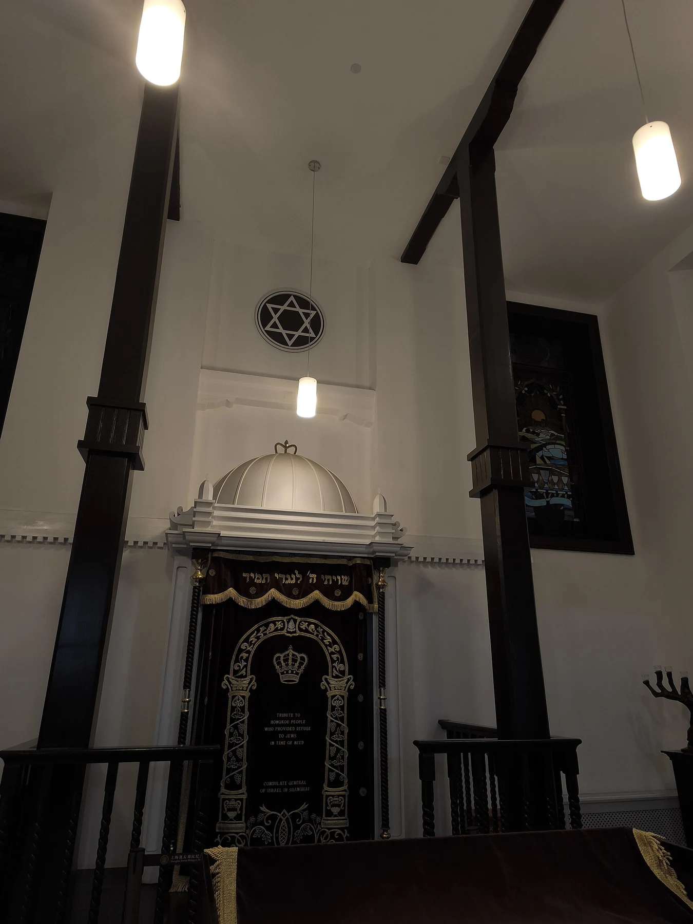 A decorative ark, tall dark columns and a small six-pointed star opening on the pale upper wall.