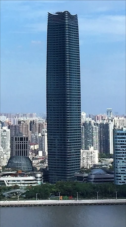 The tall tower and its curved crown seen above the opposite riverbank.