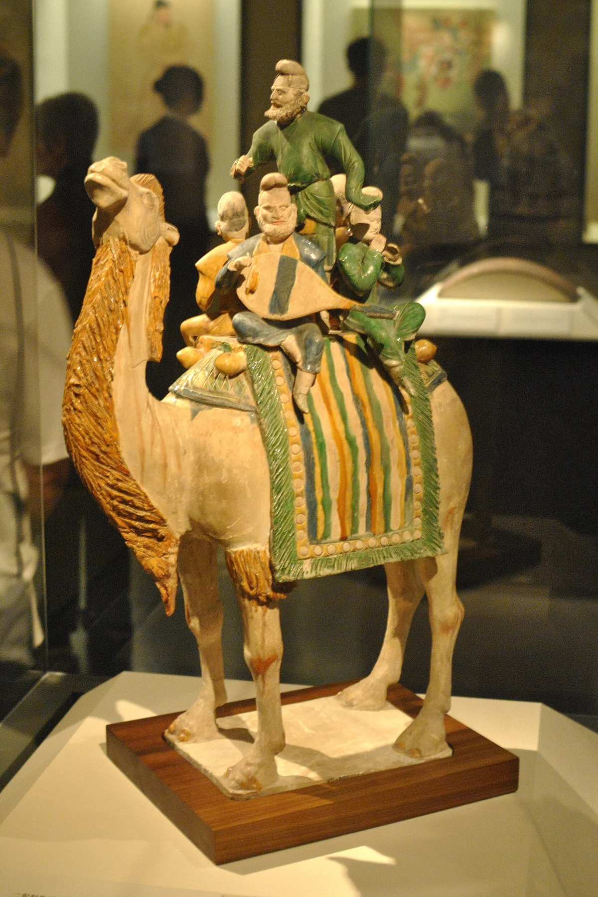 A glazed pottery camel carrying a small platform of musicians and a dancer.