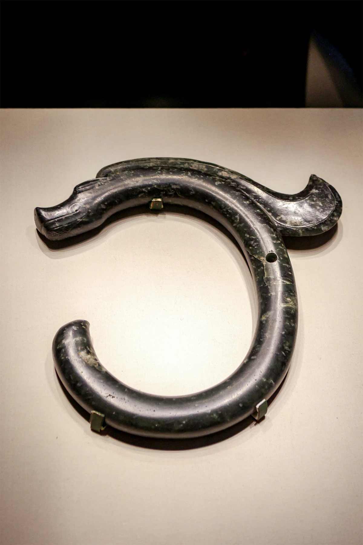 A dark jade dragon with a long snout and a curved C-shaped body.