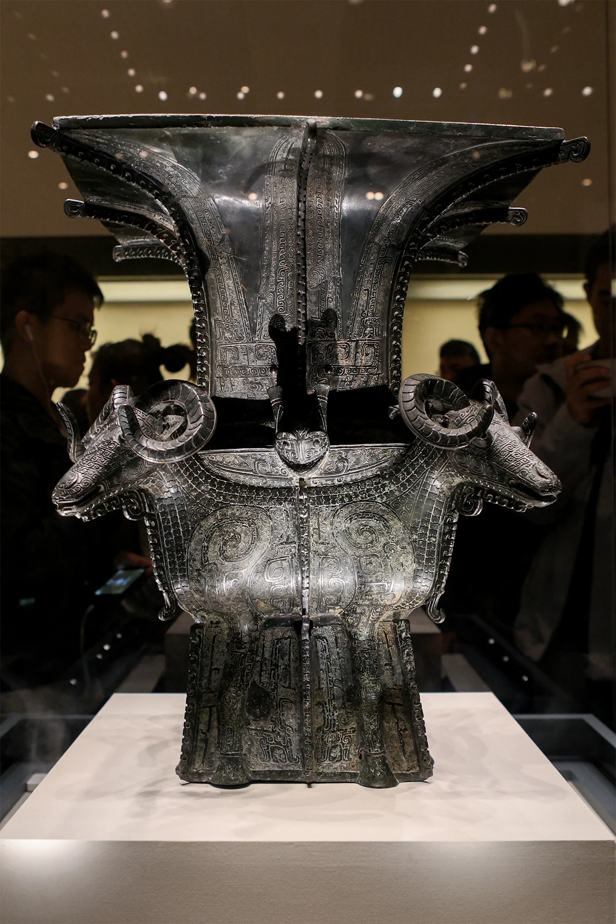 Square bronze ritual vessel with four projecting ram heads at its shoulders.