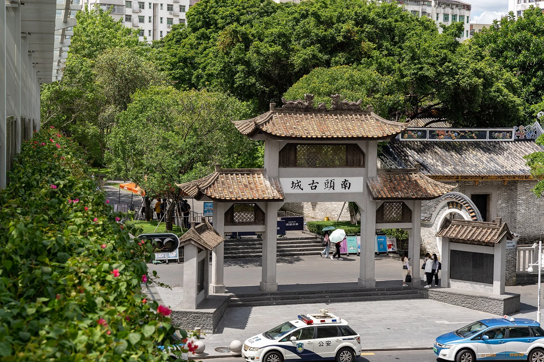 Freestanding tiled archway beside a road, trees and a wall opening