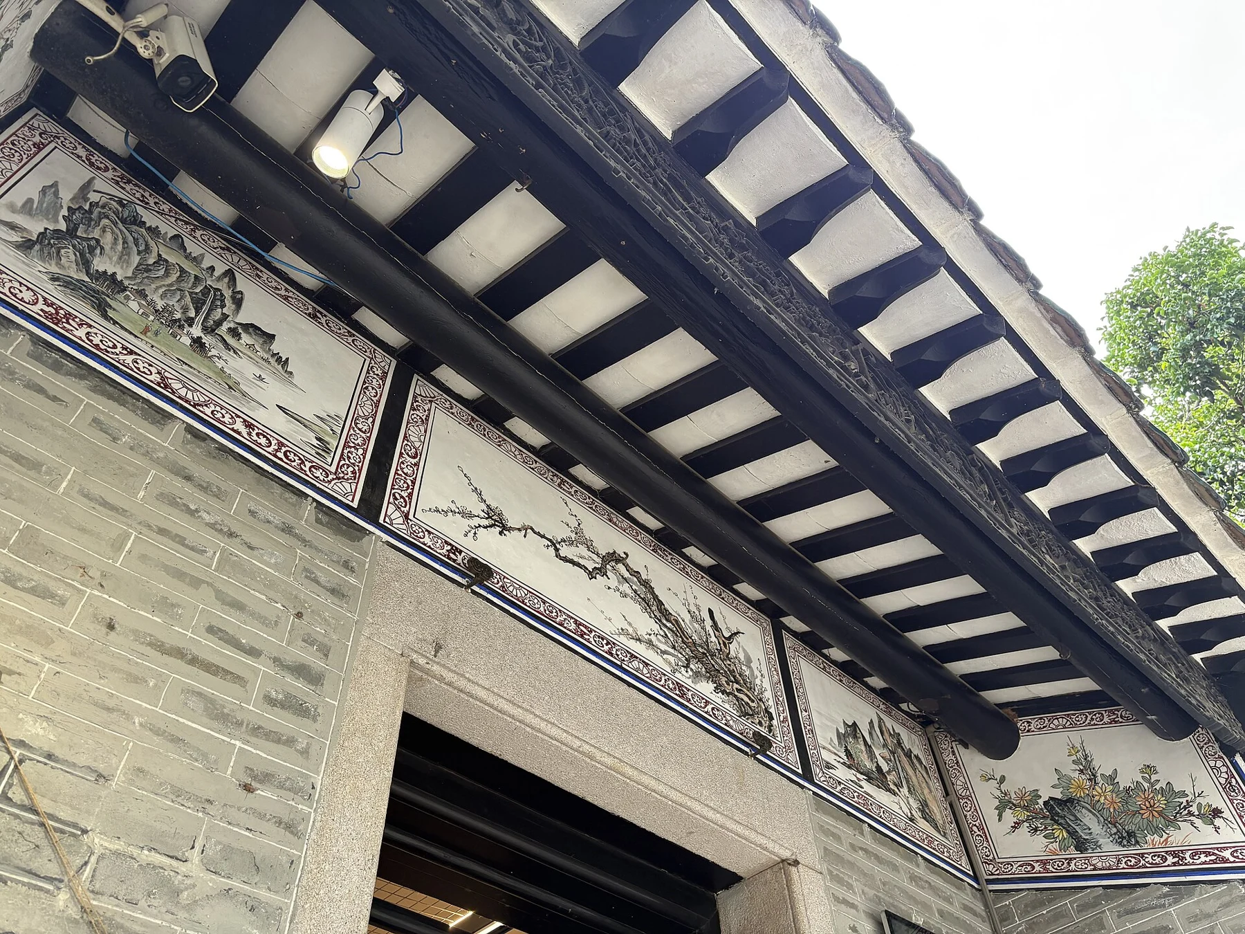 Decorative beams, painted panels, columns and tiled eaves seen from below