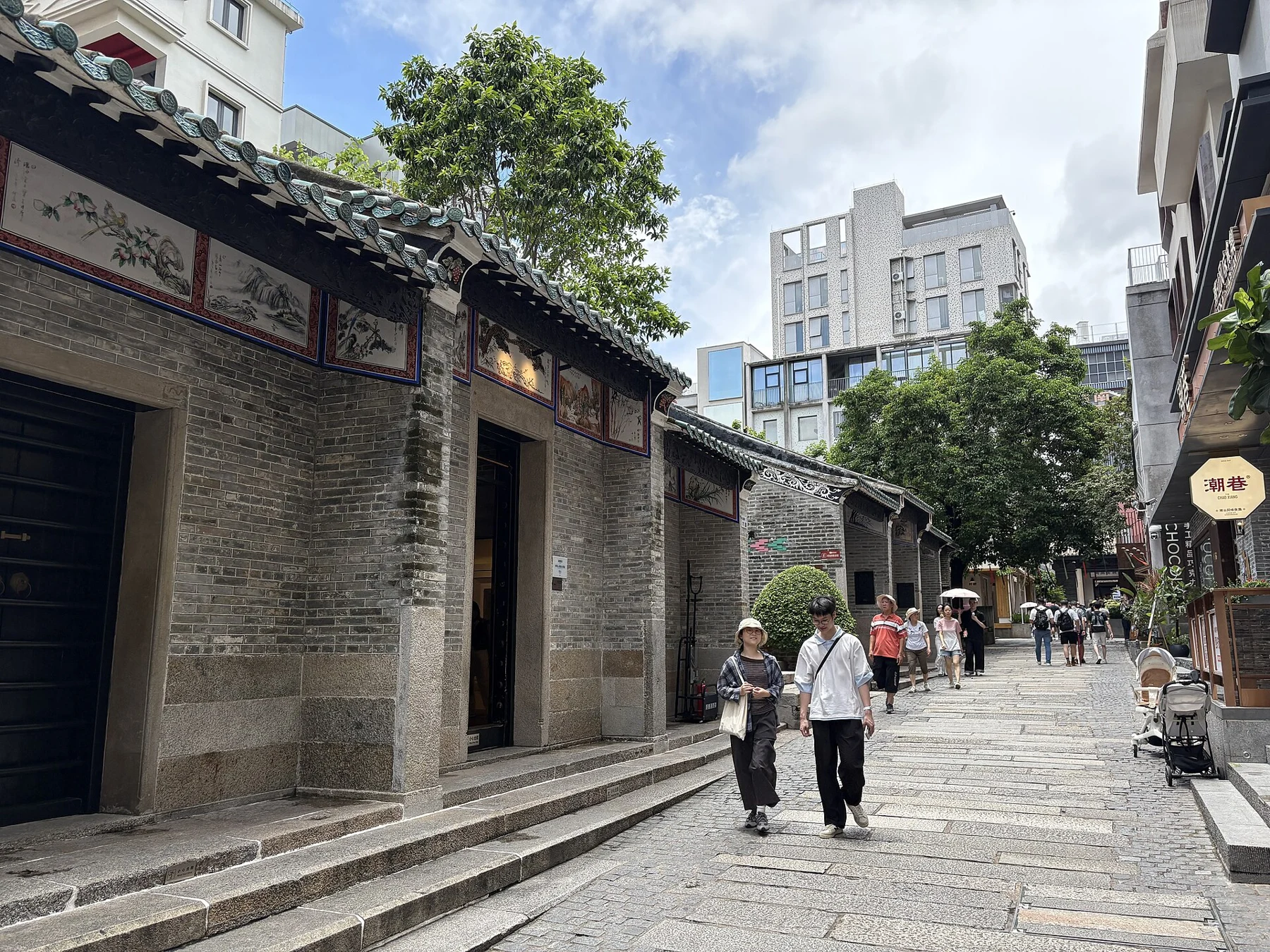 Low tiled guild-hall building beside pedestrians and taller modern buildings