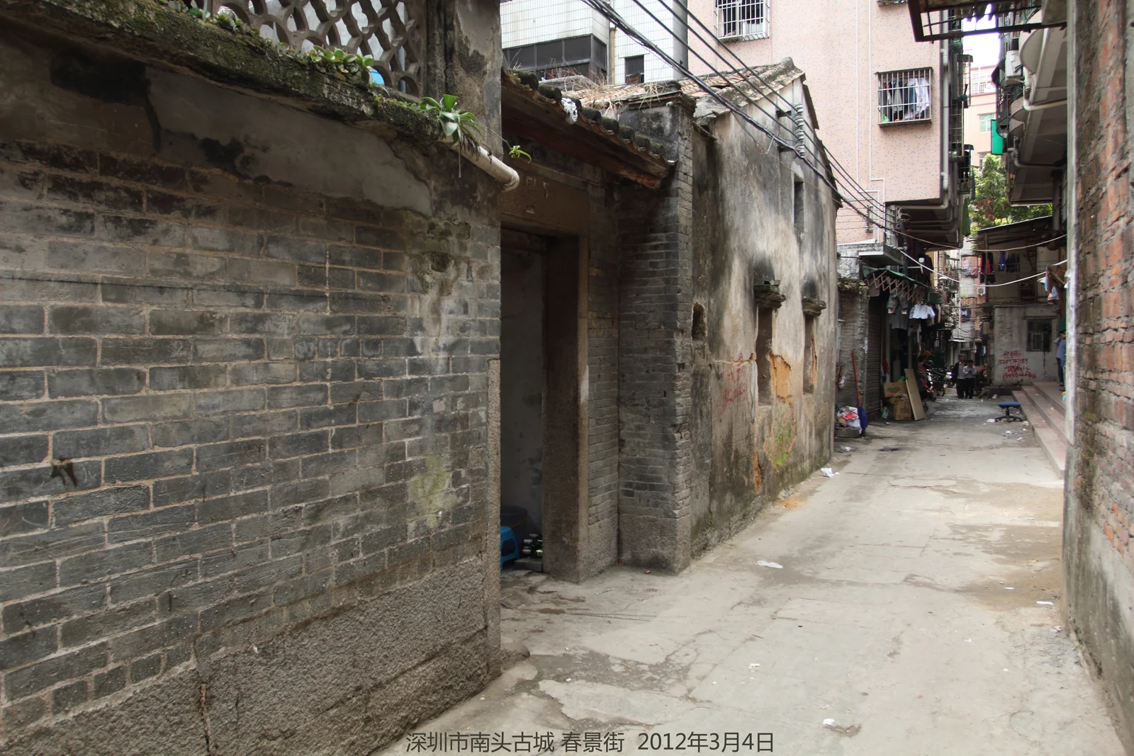 Narrow lane beside low tiled buildings and taller apartments, photographed in 2012