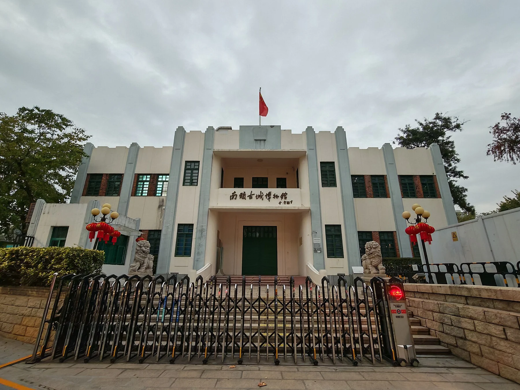 Museum façade with the Chinese museum name, green doors, stone lions and a front barrier