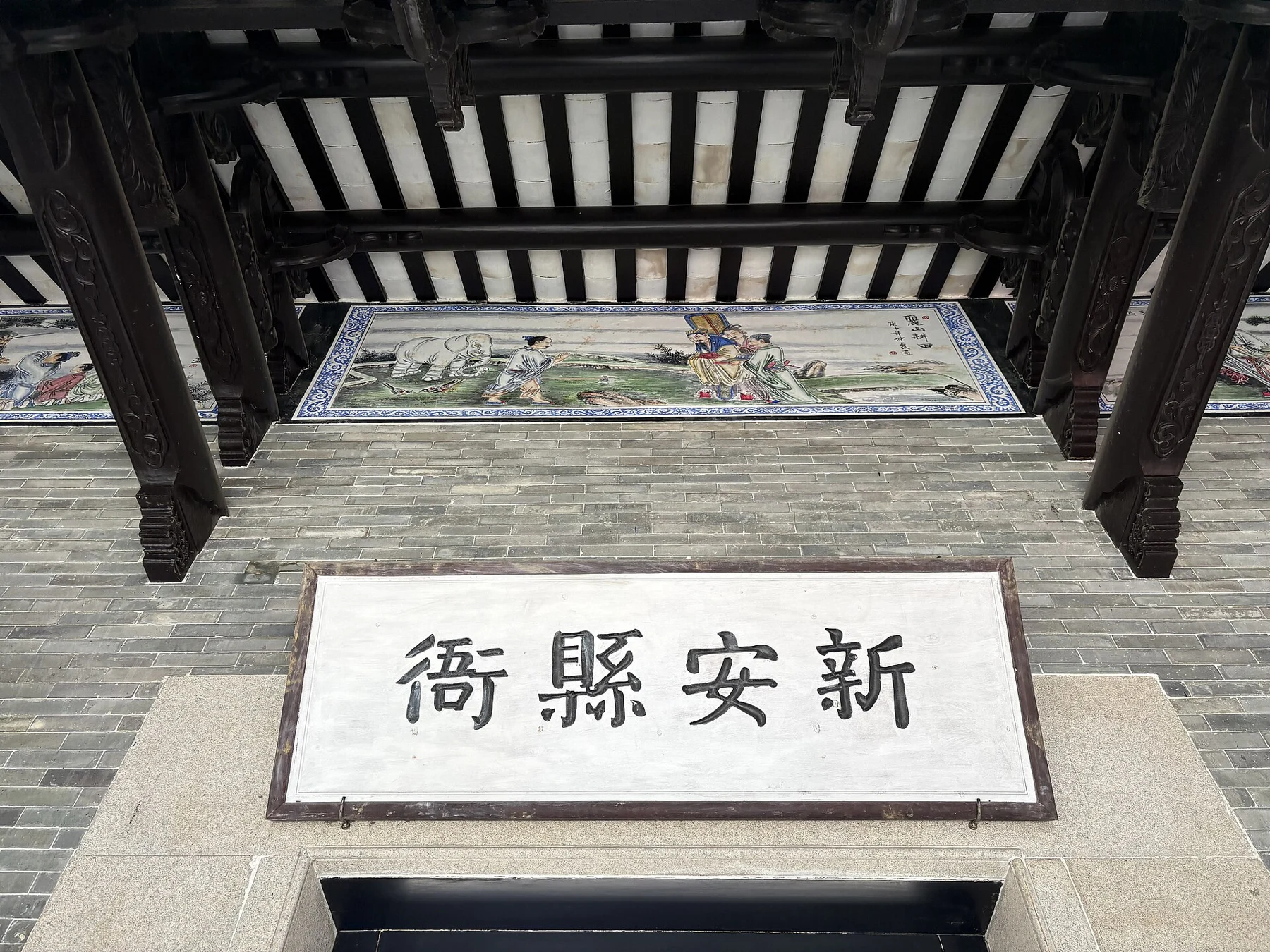 An entrance with the Chinese characters for Xin’an County Government Office and decorated beams