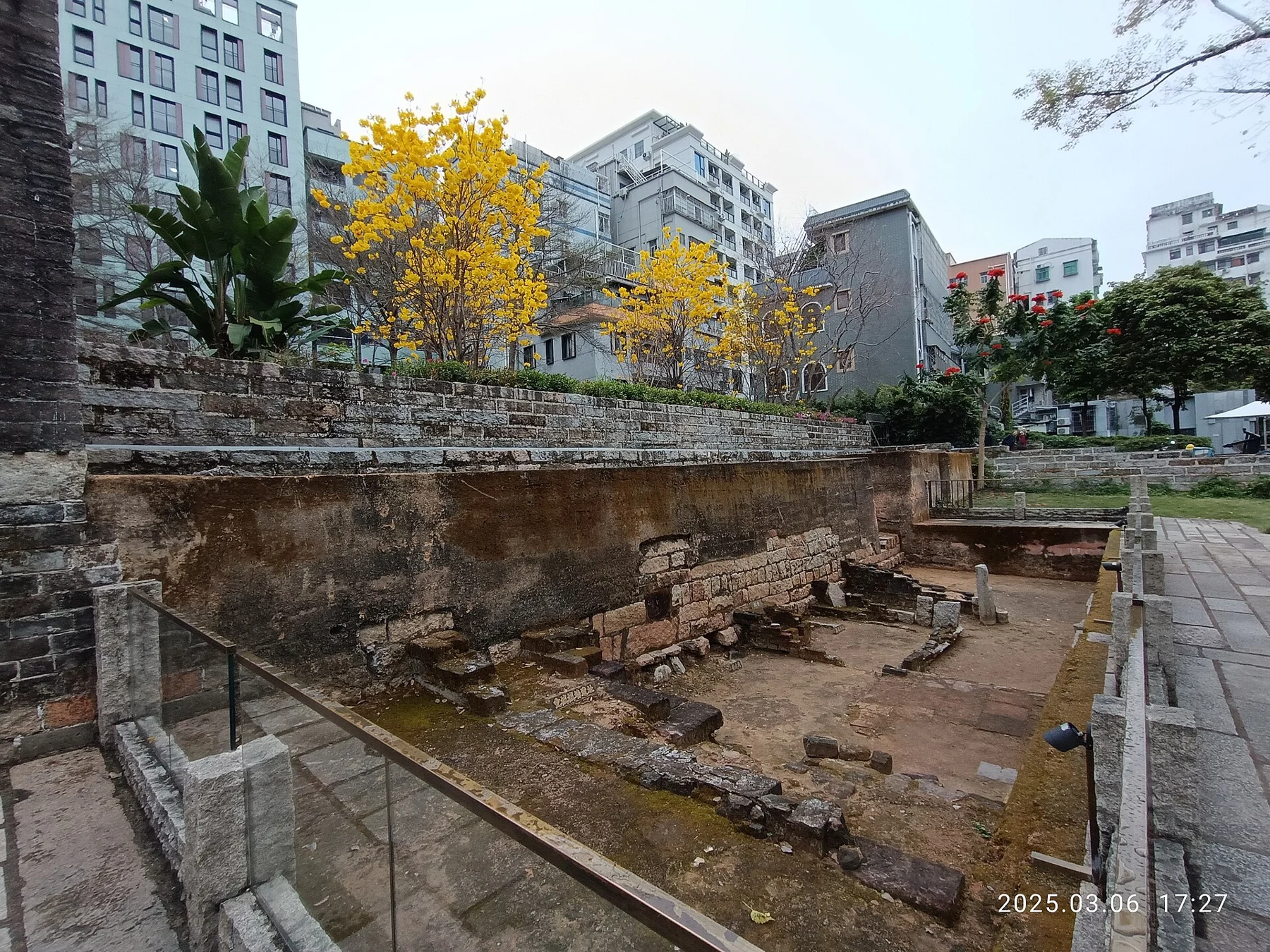 An open archaeological display of masonry and ground layers near the gate