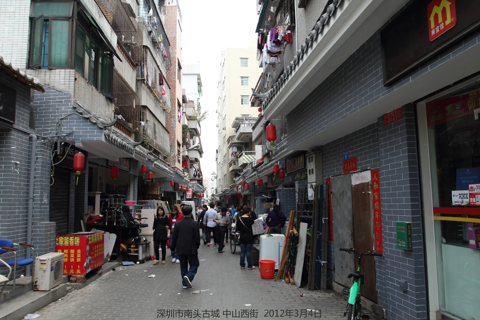 Dated 2012 street scene with shops, pedestrians, apartments and laundry above