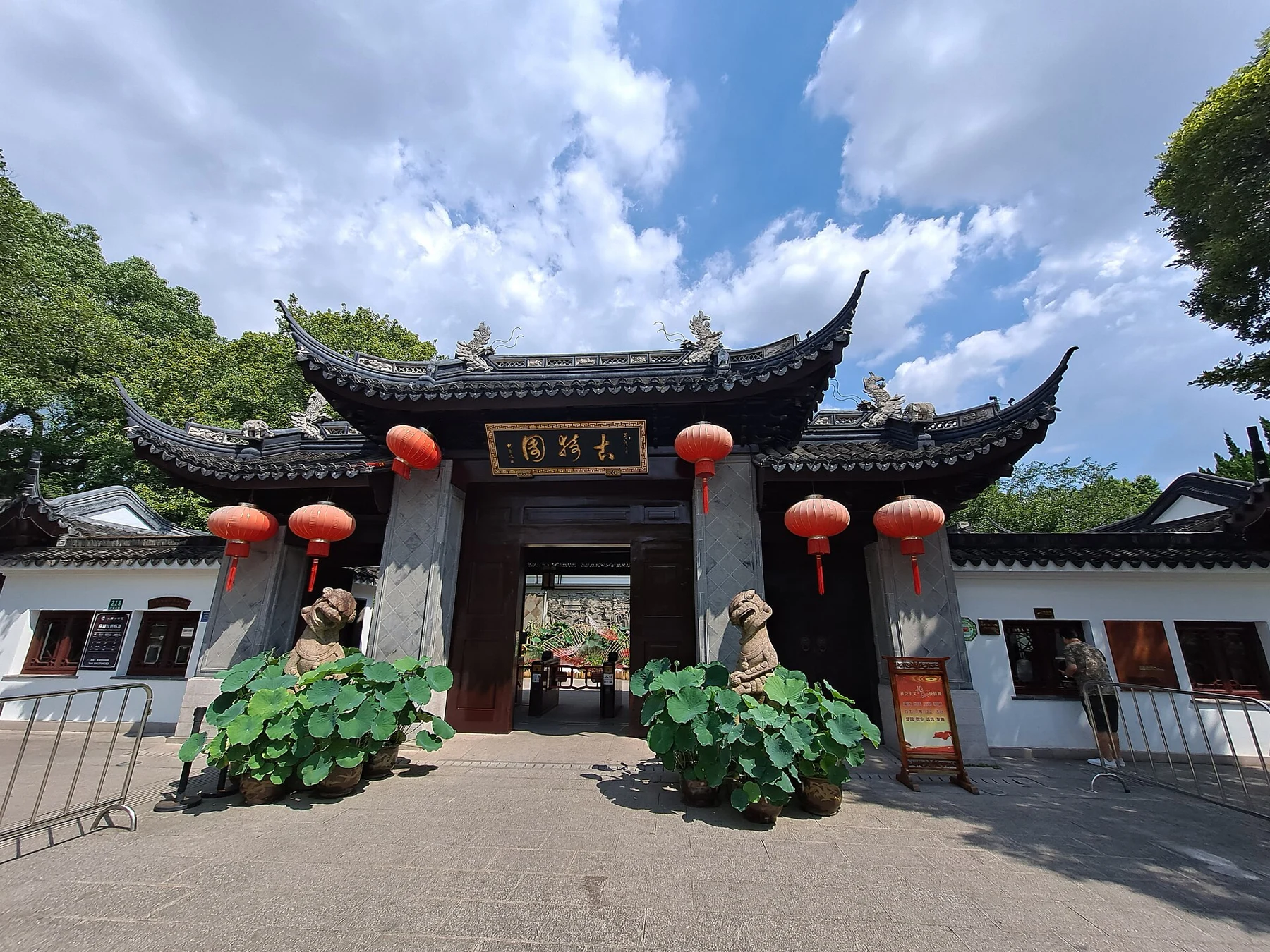 A tiled garden entrance marked with its name and flanked by red lanterns.