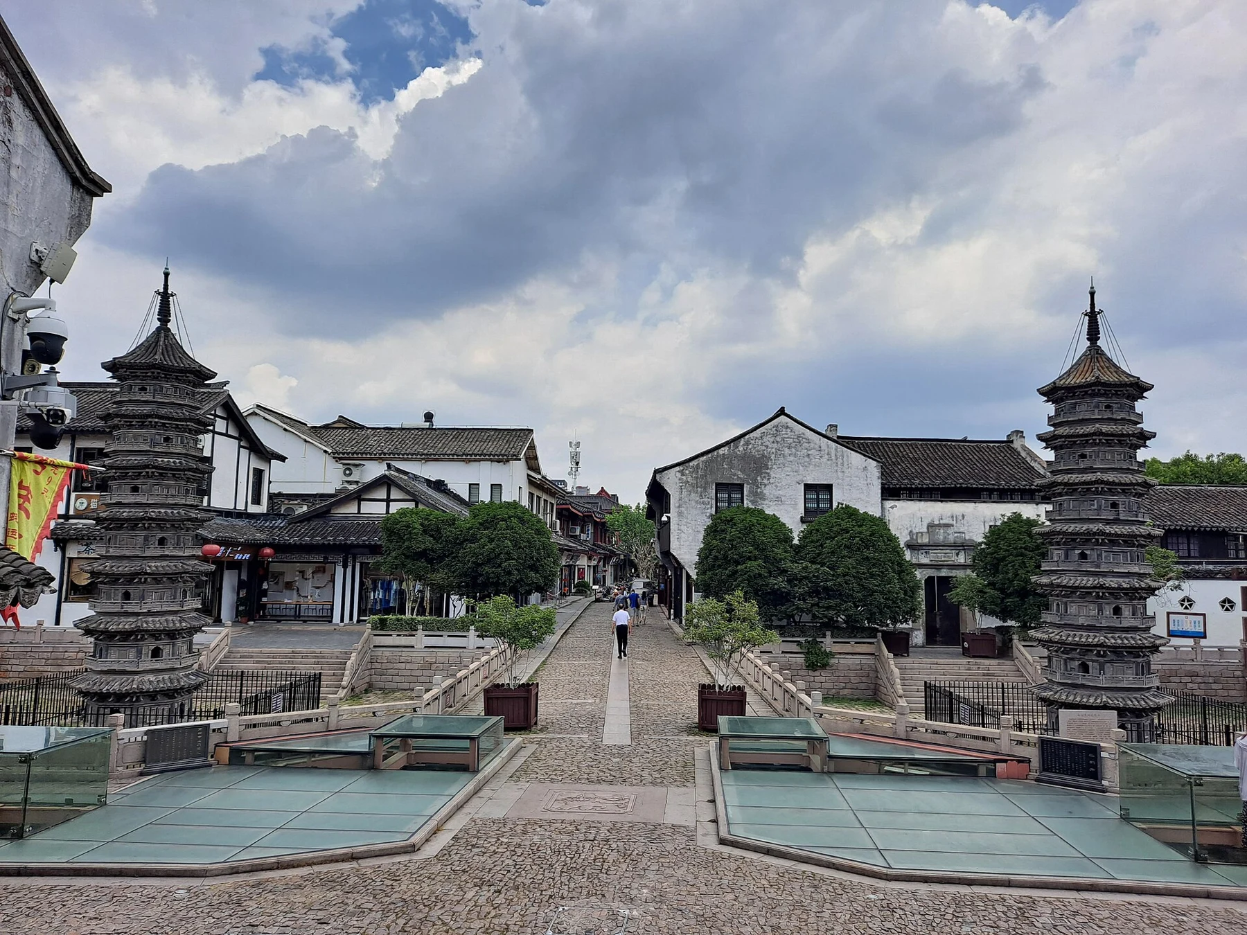 Two small multi-tiered towers standing in a recessed paved area among old-town buildings.