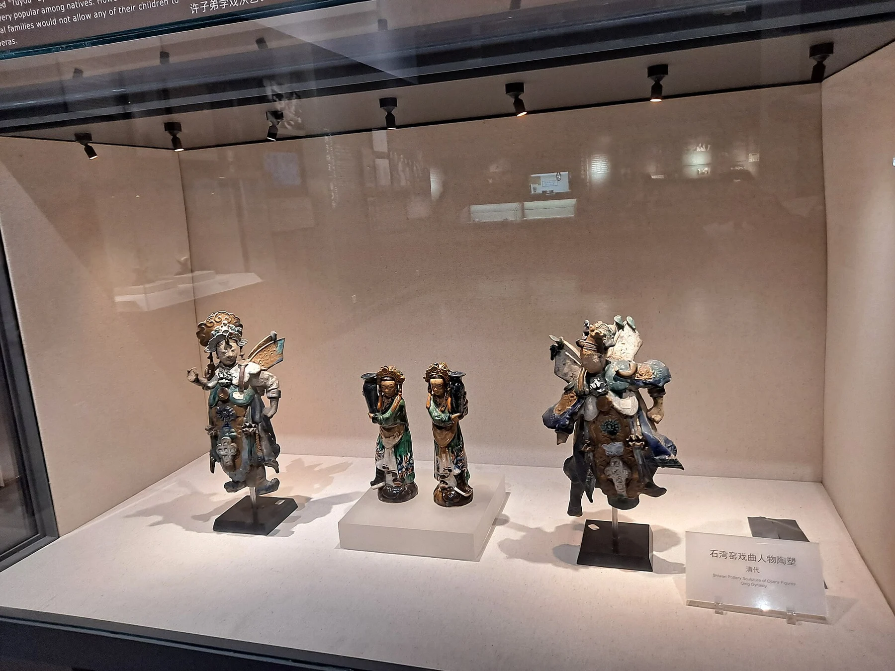 Four pottery opera figures in a museum case, with a label identifying Shiwan opera-figure sculptures of the Qing dynasty