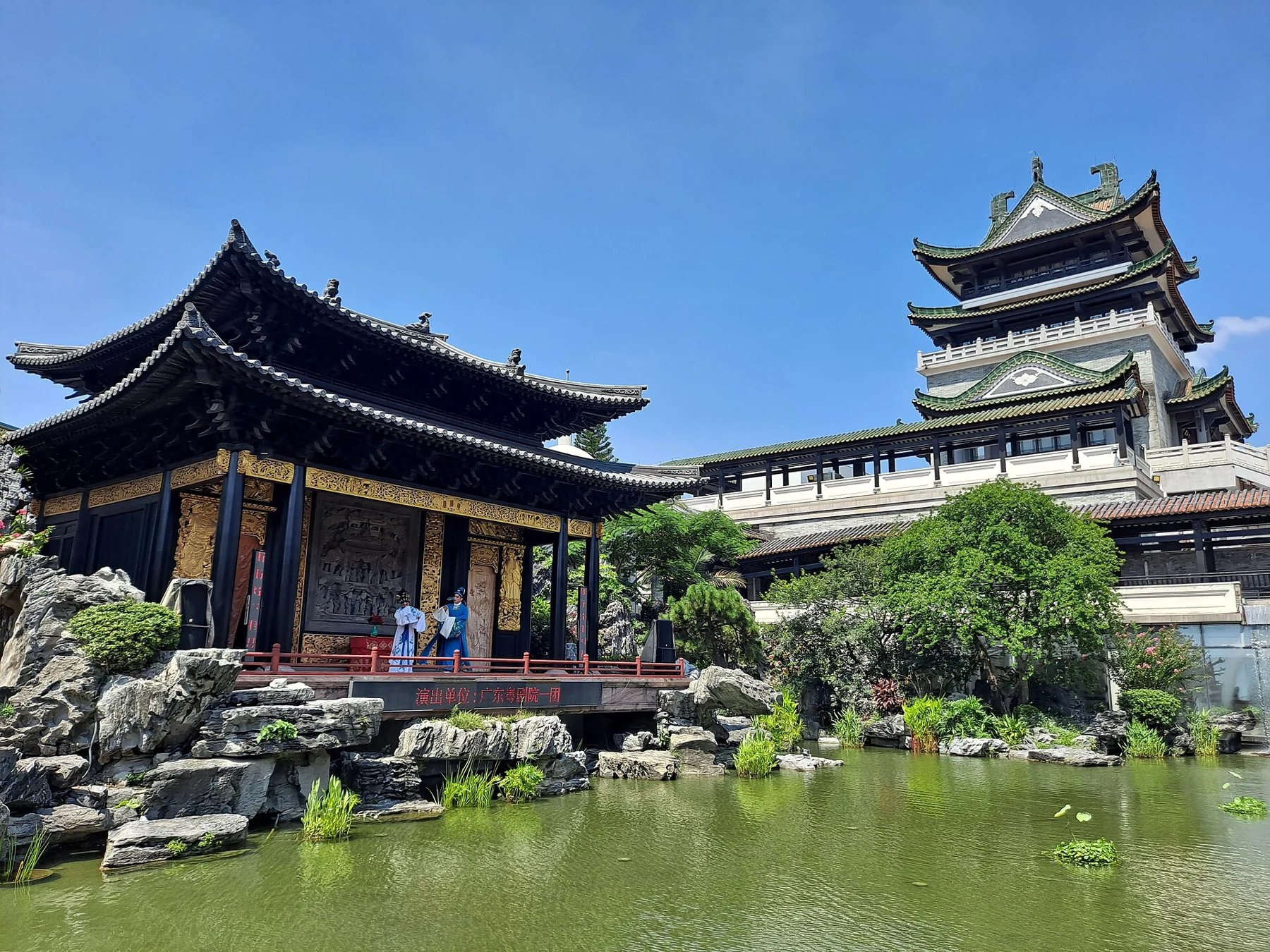 Broad view of the Cantonese Opera Art Museum garden, water-facing stage, rockwork and tower
